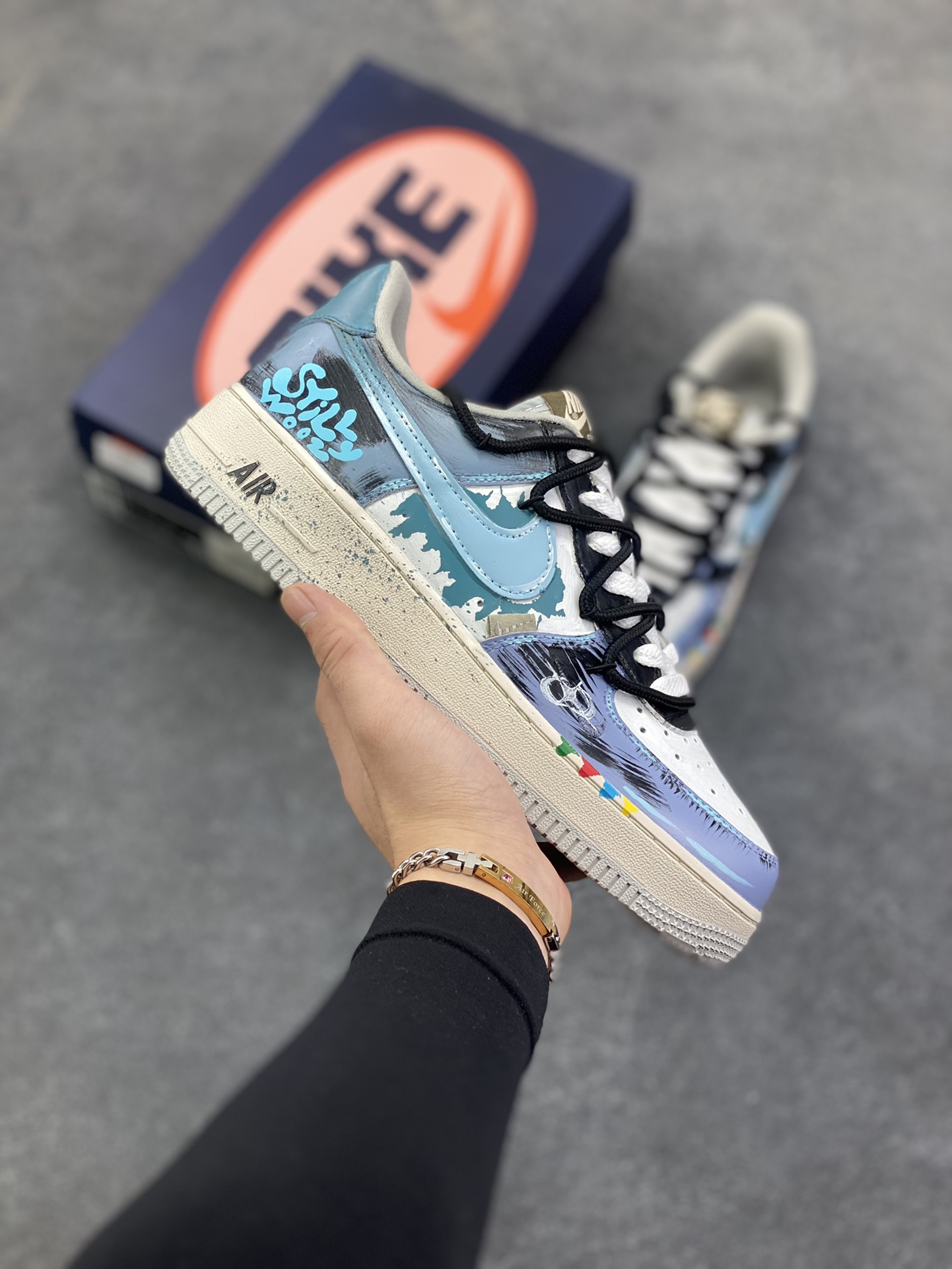 手绘涂鸦“色彩裂变”Nike Air Force 1 “Color fission”空军一号定制板鞋 当街头潮流与艺术涂鸦猛烈碰撞，便诞生了这双“色彩裂变·灰蓝艺术空军一号”。它以经典Nike Air Force 1为载体，灰、蓝、白的主色调如同艺术画布，泼墨般的色彩裂变效果打破常规，鞋身的“Still Woozy”艺术字体与鞋侧Swoosh、中底泼墨细节呼应，将随性的艺术表达注入鞋款灵魂 货号：XL2312-101 尺码：36 36.5 37.5 38 38.5 39 40 40.5 41 42 42.5 43 44 44.5 45-选品中心