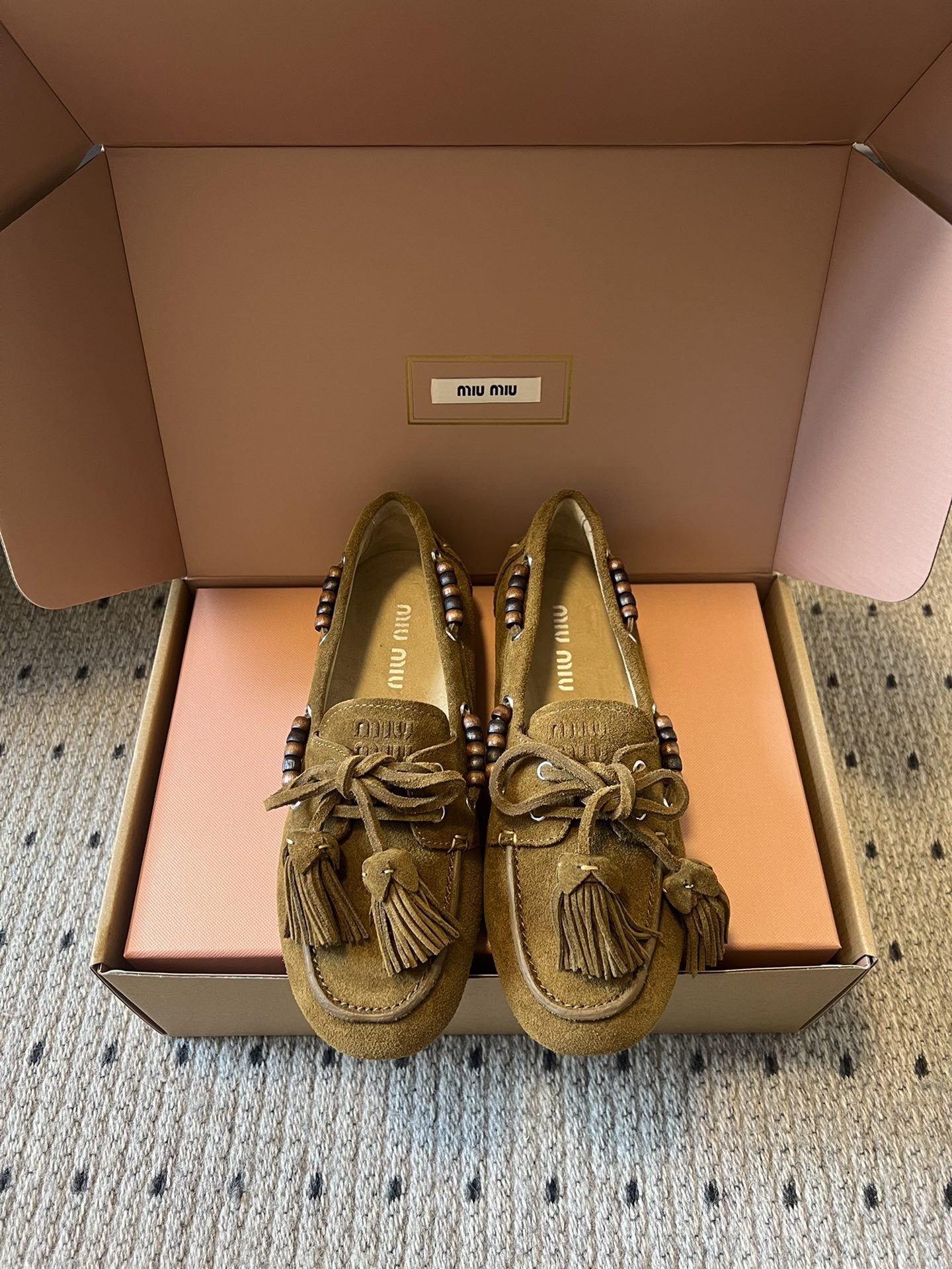 NO:759118,Miu Mi* 25FW deck shoes suede double-tassel slip-on loafers. The upper is made of suede, which is soft to the touch and has a retro texture. The side of the shoe is decorated with beaded elements, which are fixed through metal eyelets. The craftsmanship is exquisite and adds boho details. There is a tassel lace on the toe, and the combination of lace knots and tassels strengthens the retro hippie style;  The flat-soled design ensures a comfortable foot feel, and the shoe shape is loose and does not squeeze the feet, making it suitable for long-term daily wear; the softness of the suede leather further enhances the wearing comfort. The insole of the shoe is printed with a clear 'miu miu' brand logo, highlighting the brand recognition and texture. The upper is suede and the lining is cowhide. The rubber outsole is increased by 2cm. Size35-40, loafers, miumiu, loafers, cowhide, chamois leather19860909Miu Mi* 25FW deck shoes 麂皮双流苏一脚蹬乐福鞋 鞋面采用反绒皮材质,触感柔软且自带复古质感；鞋侧装饰有串珠元素,通过金属孔眼固定,工艺精致,增添波西米亚风细节.鞋头处设有流苏系带,系带结与流苏的组合强化了复古嬉皮风格； 平底设计保障舒适脚感,鞋型宽松不挤脚,适合日常长时间穿着；反绒皮的柔软度进一步提升穿着舒适度.鞋内底印有清晰的“miu miu”品牌logo,彰显品牌辨识度与质感. 鞋面牛反绒 内里牛皮 大底橡胶大底 增高2cm Size35-40,乐福鞋,miumiu,loafers,cowhide,chamois leather,Women's Shoes