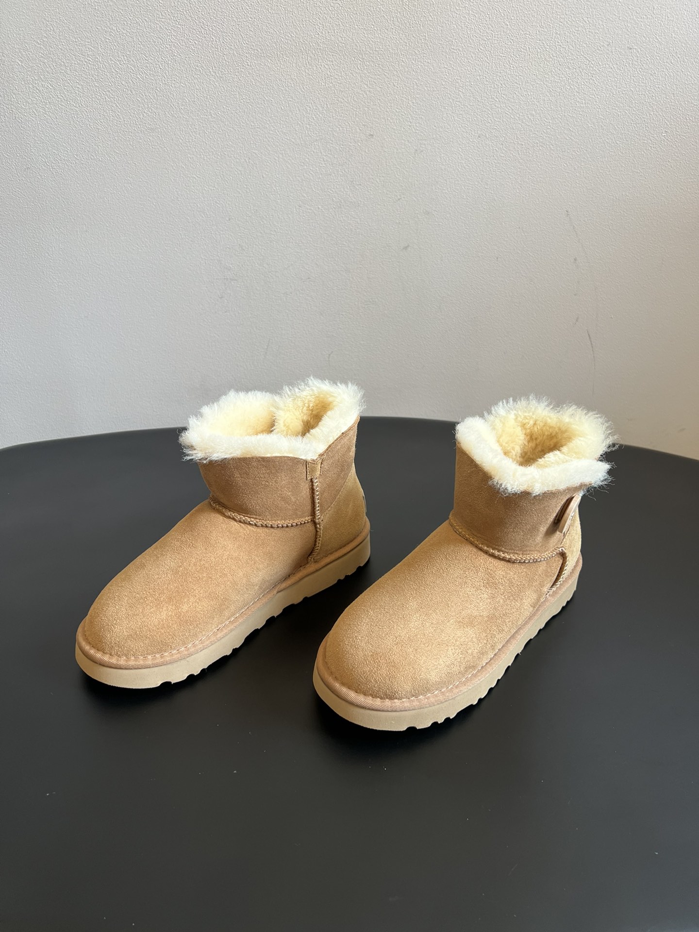 UG* 秋冬保暖圆扣logo短款雪地靴采用羊皮毛一体材质，鞋面是质感细腻的反绒皮，内里填充柔软的羊毛，既