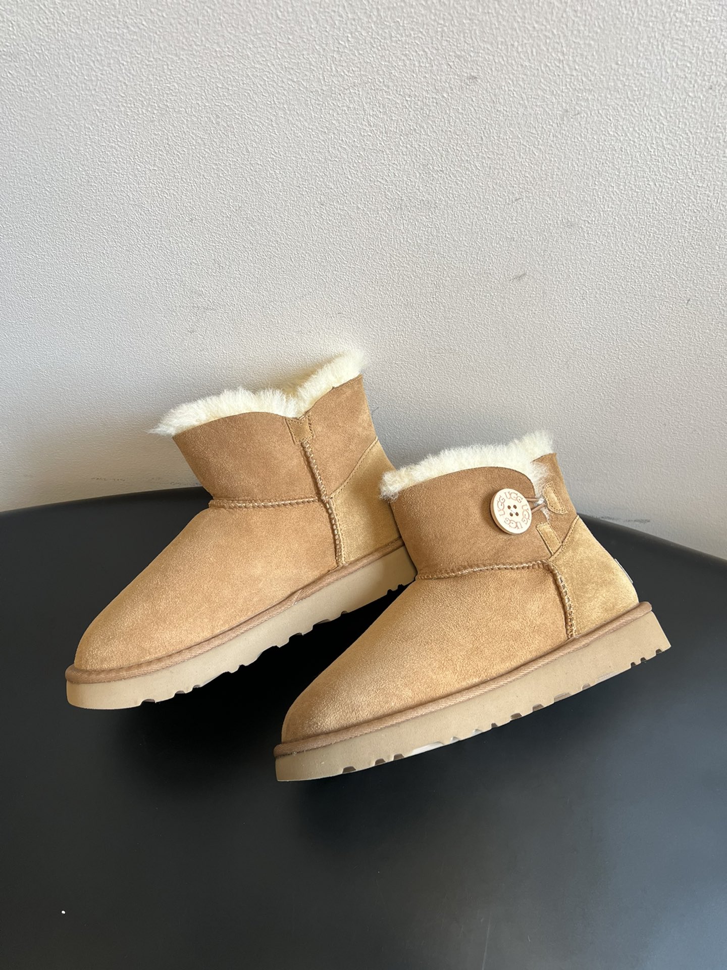 UG* 秋冬保暖圆扣logo短款雪地靴采用羊皮毛一体材质，鞋面是质感细腻的反绒皮，内里填充柔软的羊毛，既