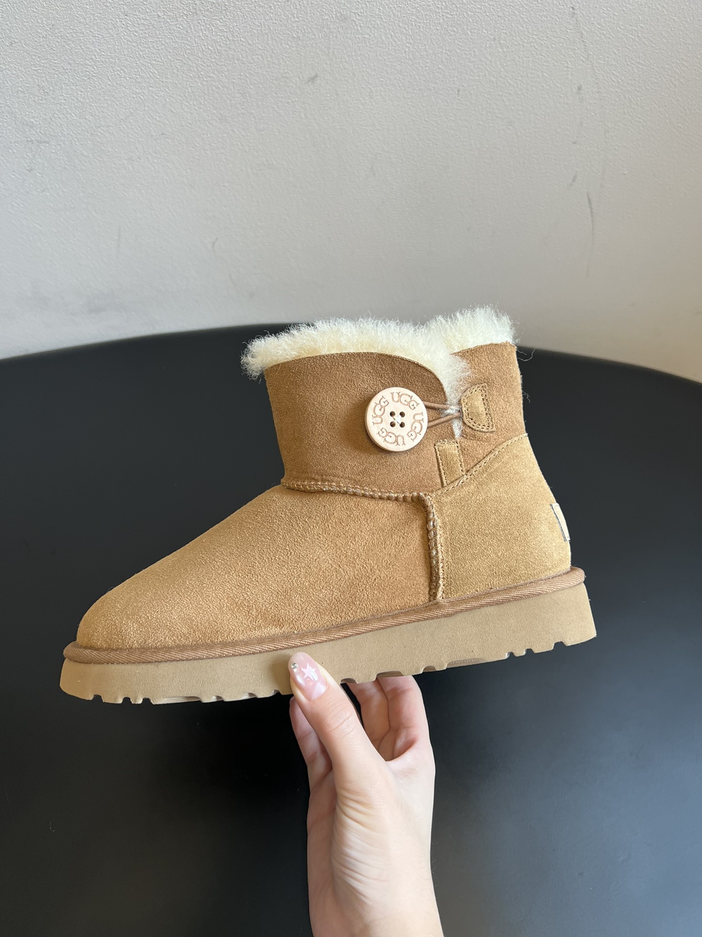 UG* 秋冬保暖圆扣logo短款雪地靴采用羊皮毛一体材质，鞋面是质感细腻的反绒皮，内里填充柔软的羊毛，既