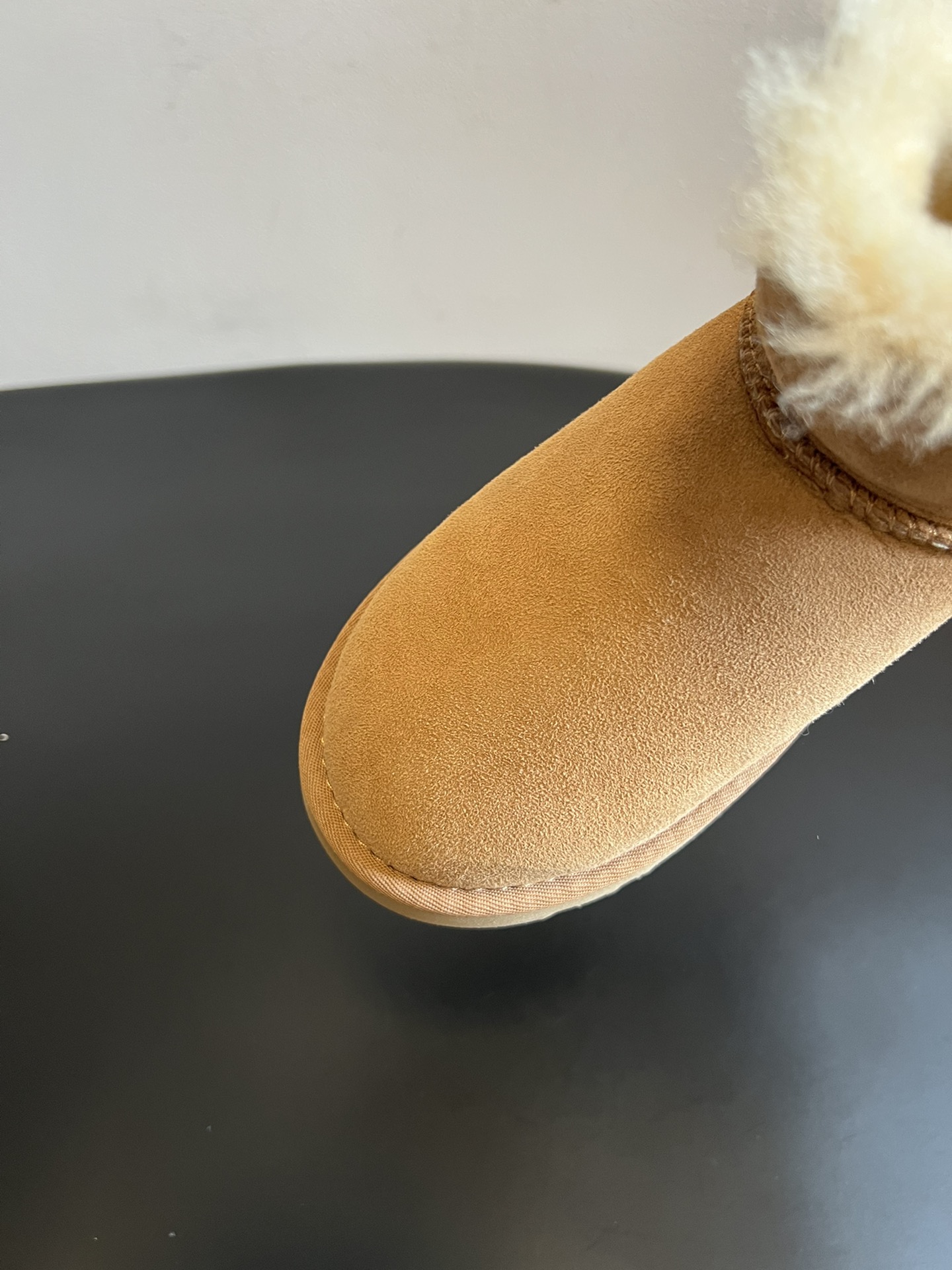 UG* 秋冬保暖圆扣logo短款雪地靴采用羊皮毛一体材质，鞋面是质感细腻的反绒皮，内里填充柔软的羊毛，既