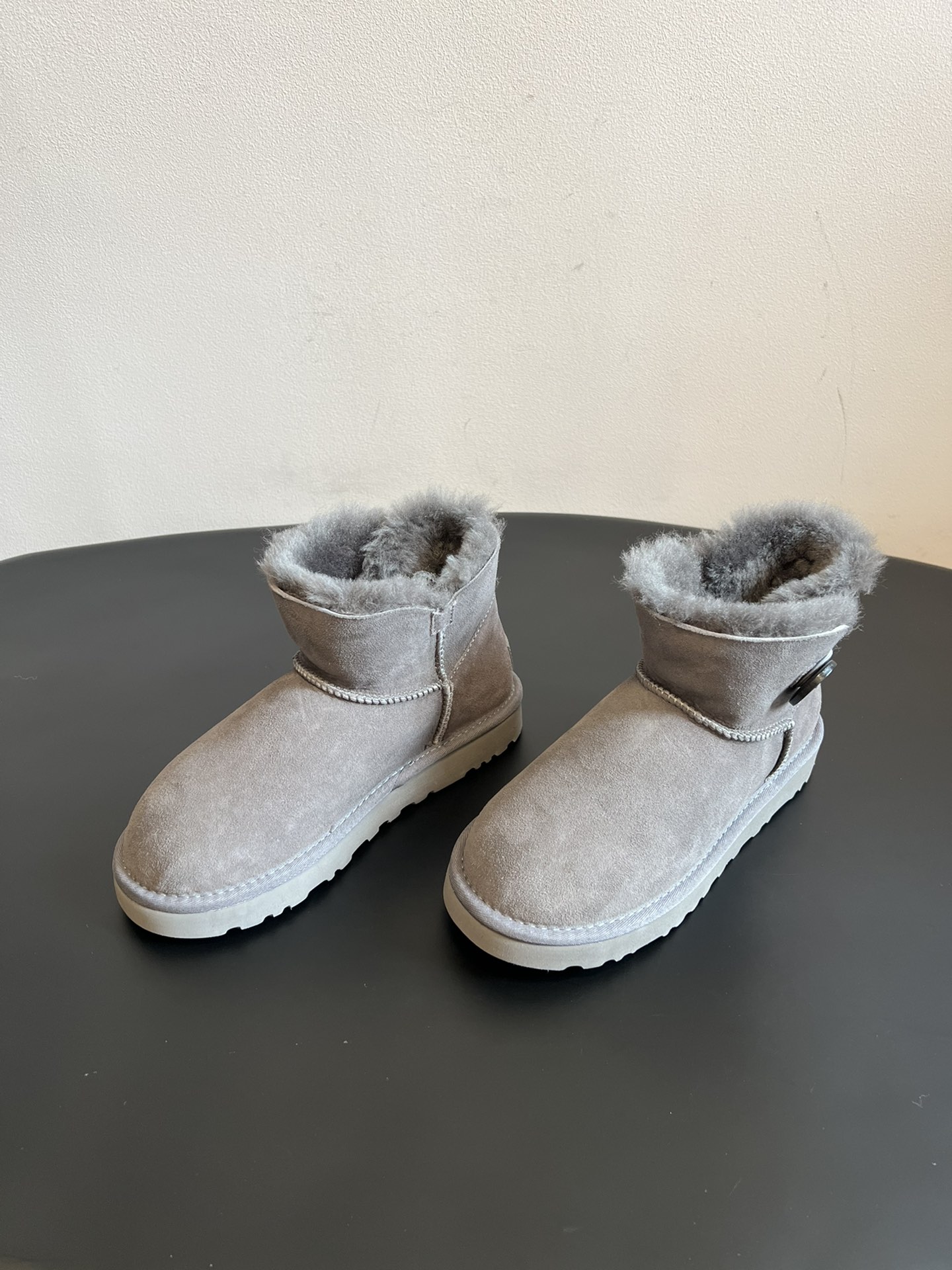 UG* 秋冬保暖圆扣logo短款雪地靴采用羊皮毛一体材质，鞋面是质感细腻的反绒皮，内里填充柔软的羊毛，既