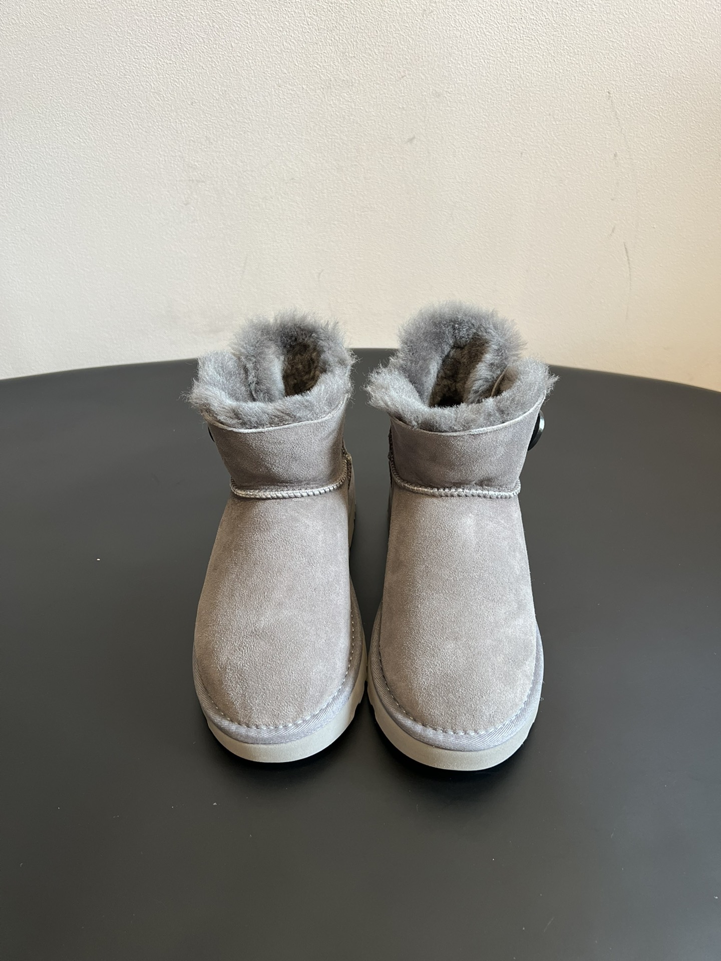 UG* 秋冬保暖圆扣logo短款雪地靴采用羊皮毛一体材质，鞋面是质感细腻的反绒皮，内里填充柔软的羊毛，既