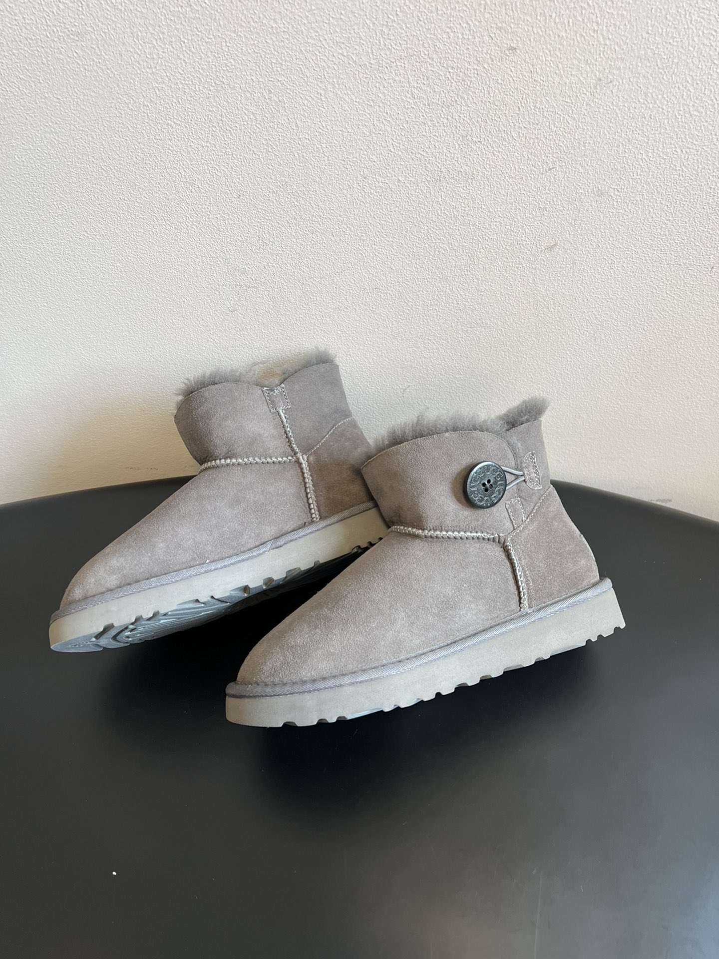 UG* 秋冬保暖圆扣logo短款雪地靴采用羊皮毛一体材质，鞋面是质感细腻的反绒皮，内里填充柔软的羊毛，既