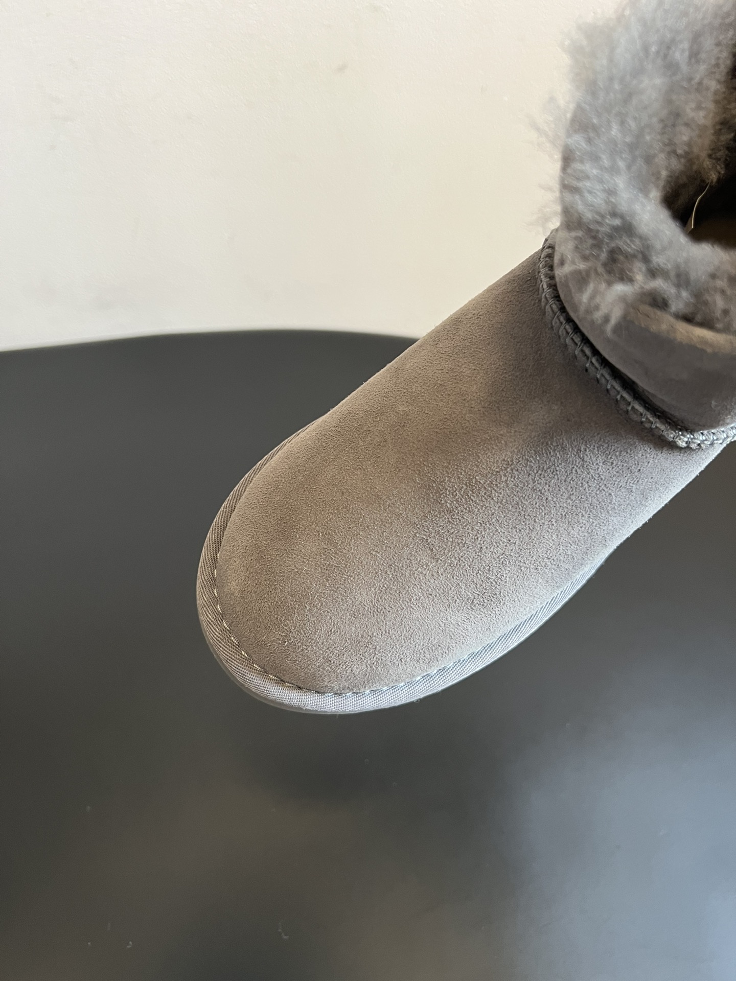 UG* 秋冬保暖圆扣logo短款雪地靴采用羊皮毛一体材质，鞋面是质感细腻的反绒皮，内里填充柔软的羊毛，既