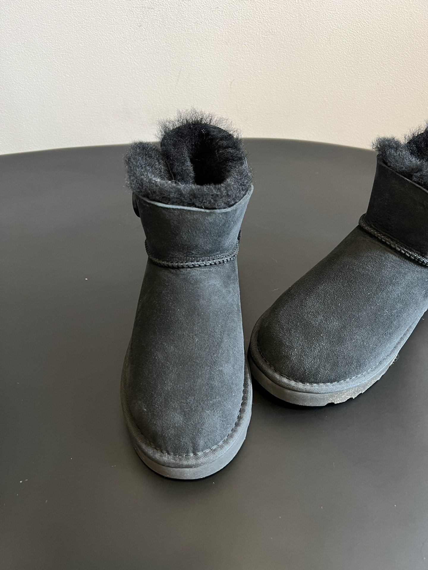 UG* 秋冬保暖圆扣logo短款雪地靴采用羊皮毛一体材质，鞋面是质感细腻的反绒皮，内里填充柔软的羊毛，既