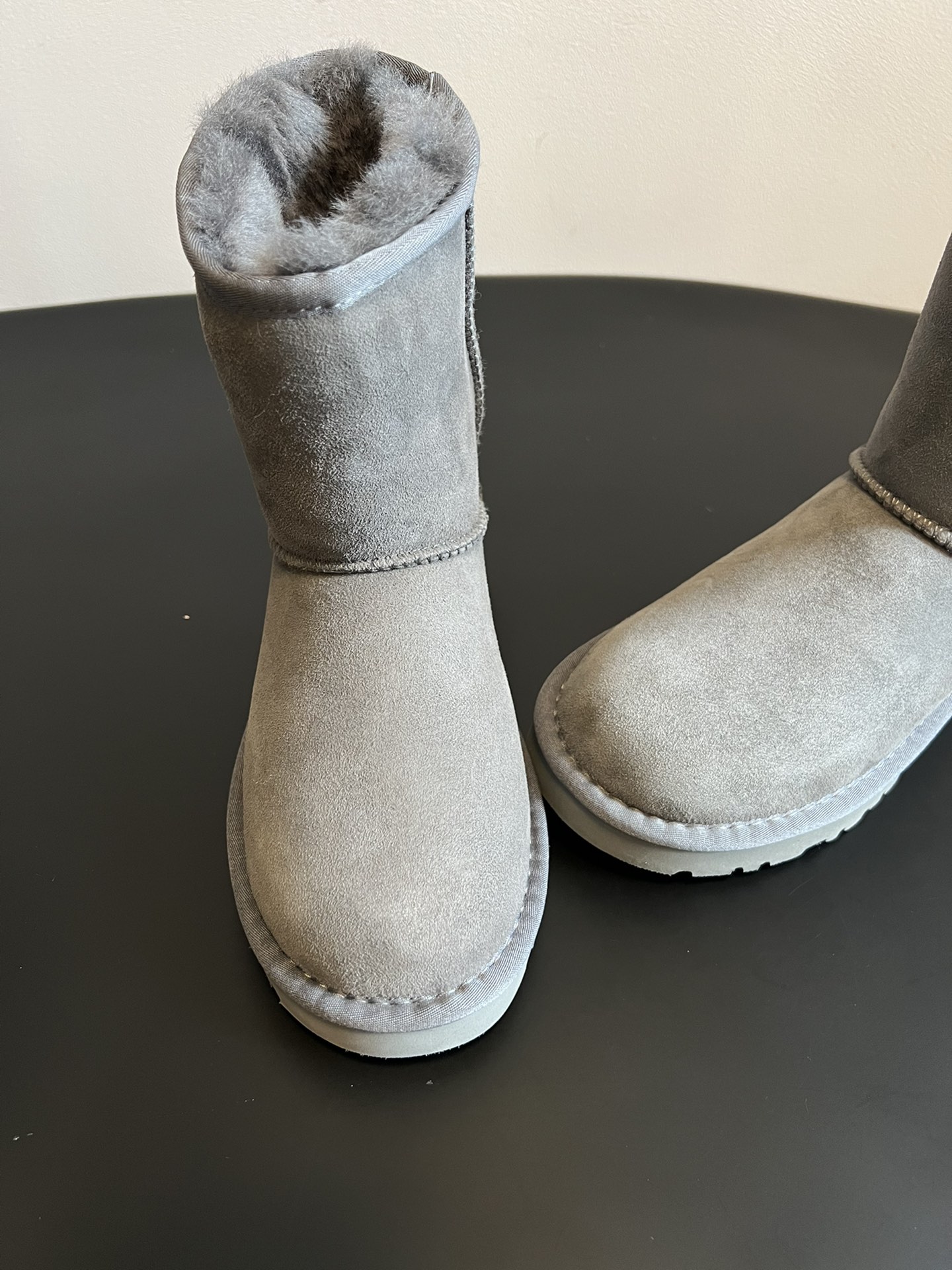 UG* 秋冬保暖圆头雪地靴鞋面采用翻毛皮材质，内里填充羊毛，实现保暖与质感的结合。中筒靴型搭配侧边扣带设