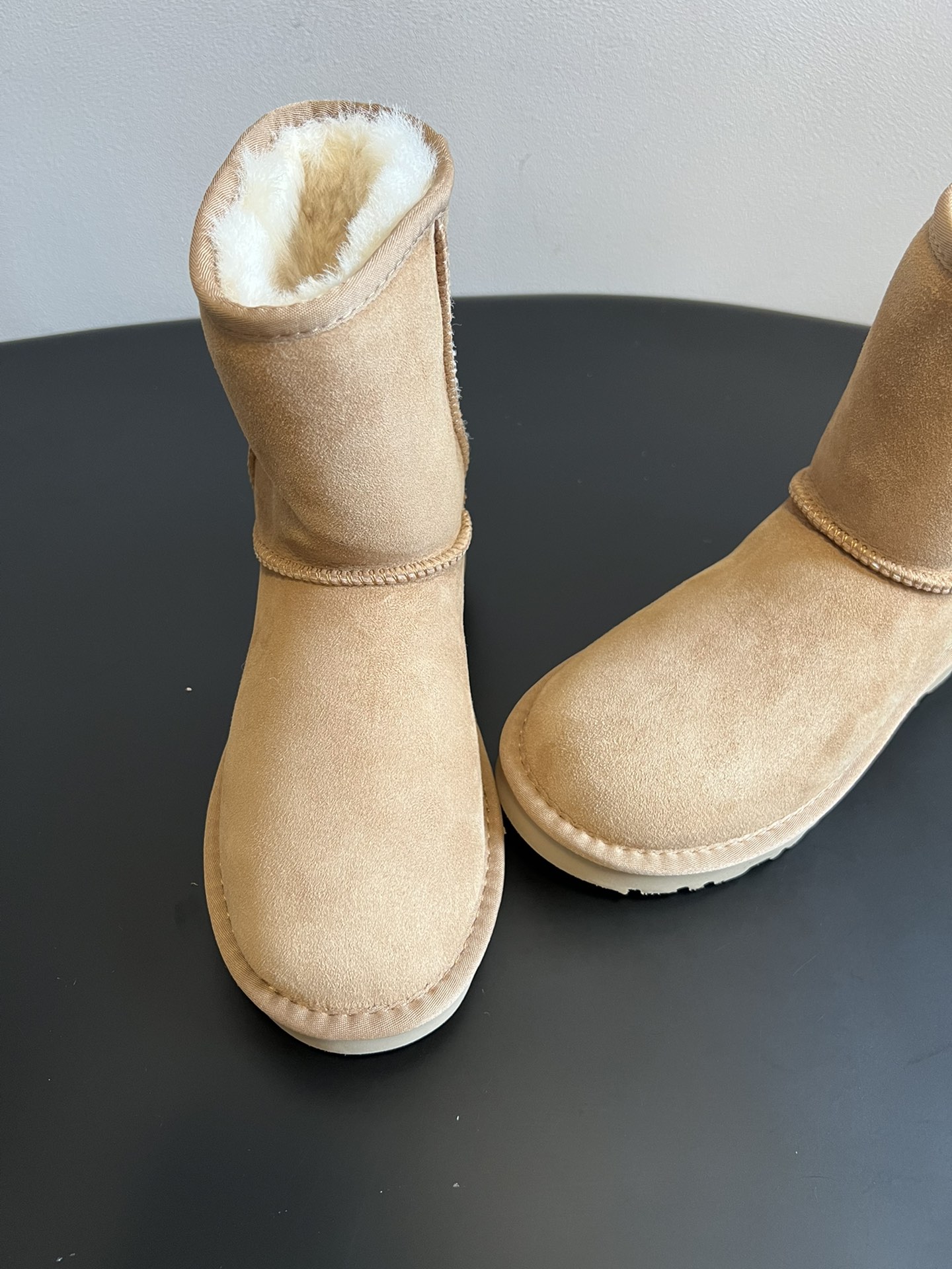 UG* 秋冬保暖圆头雪地靴鞋面采用翻毛皮材质，内里填充羊毛，实现保暖与质感的结合。中筒靴型搭配侧边扣带设