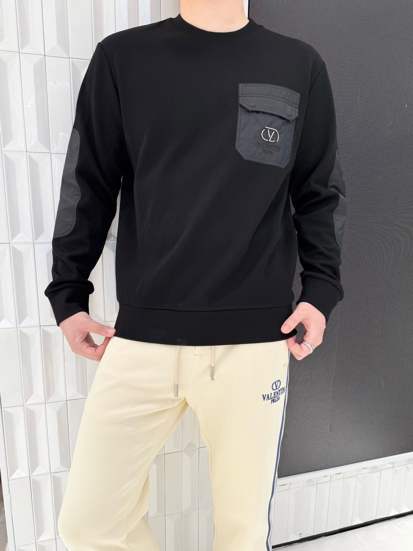 NO:595054,Valentino-2025 high-end new sweater!  The main body is made of skin-friendly modal cotton wool fabric, which is soft and breathable, and comfortable to wear without restraint; the pockets and elbows are made of special material, which is wear-resistant and shiny, improving the overall texture and practicality. The black main tone is classic and versatile, and the round neck design is simple and elegant; the spliced chest pockets have the brand 'VALENTIN'  PRLUO' logo, the elbow splicing design adds workwear style elements, and the details highlight individuality, making the simple style more fashionable and recognizable. Size: 50-56 (model 180/140 wears 50, with Hong Kong Lane Crawford gift box packaging),,valentino,valentino,sweaters,alexander wang19860909华伦天奴-2025高端新款毛衣！主体采用亲肤莫代尔棉质羊毛面料触感柔软透气,穿着舒适无束缚；口袋及肘部拼接的特殊材质,耐磨且富有光泽,提升整体质感与实用性.黑色主调经典百搭,圆领设计简约大气；胸前拼接口袋带有品牌“VALENTIN PRLUO”标识,肘部拼接设计增添工装风元素,细节处彰显个性,让简约款型更具潮流辨识度.码数:50-56(模特180/140穿50,配香港连卡佛礼盒包装）,,valentino,valentino,sweaters,alexander wang,Men's clothing