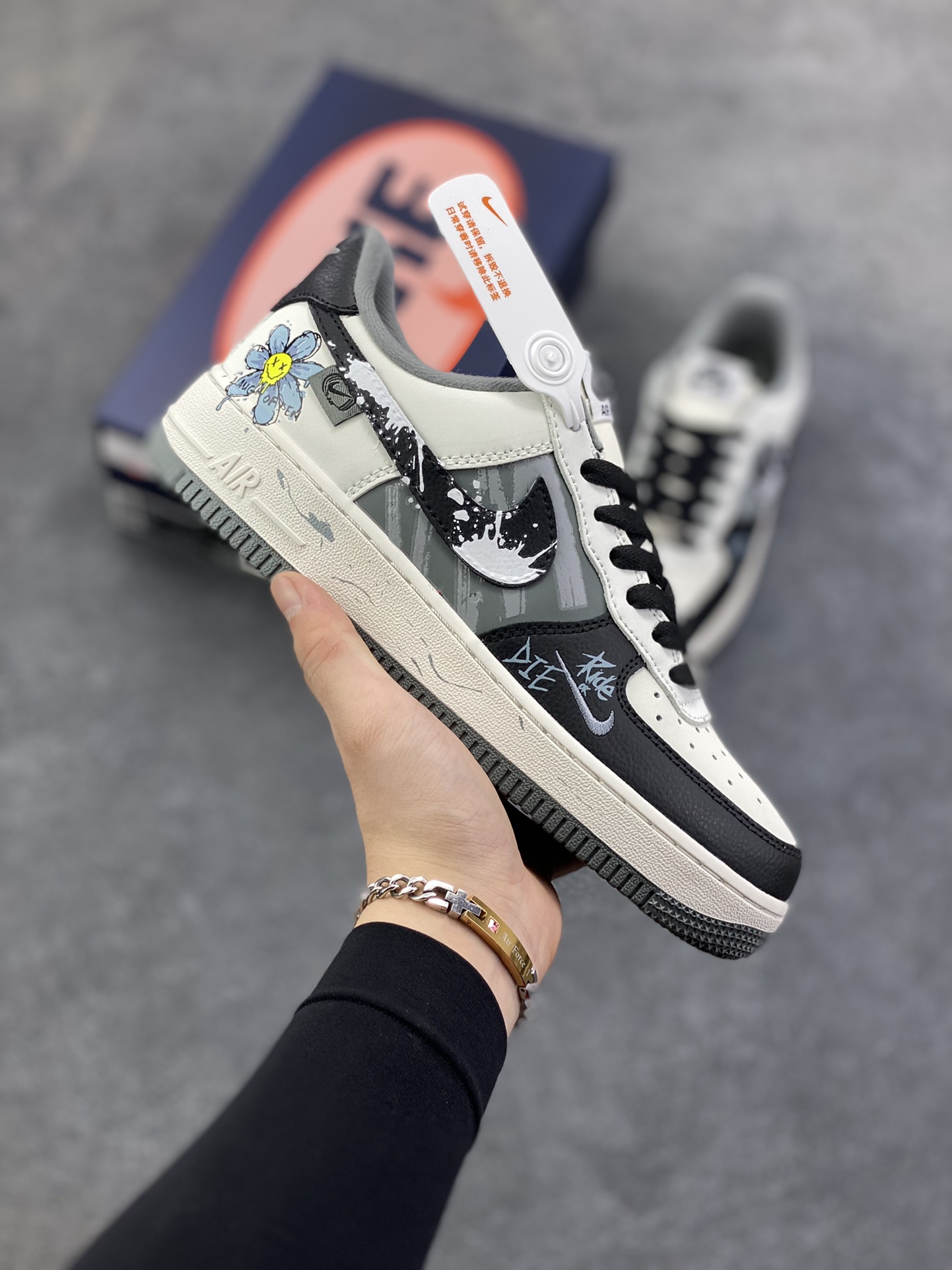 手绘涂鸦“墨绘花迹”Nike Air Force 1 “Floral traces”空军一号定制板鞋 一双将街头涂鸦与温柔意象揉碎重组的Air Force 1——鞋身以米白作底，如未干的宣纸承托着黑白泼墨般的涂鸦纹理，笔触随性却带着少年式的莽撞张力；侧身突然跳出的嫩黄小花与淡蓝花瓣，像草稿本角落不经意的温柔涂鸦，消解了街头感的冷硬，让“酷”里裹了点软乎乎的鲜活 货号：DB3301-606 尺码：36 36.5 37.5 38 38.5 39 40 40.5 41 42 42.5 43 44 44.5 45-选品中心