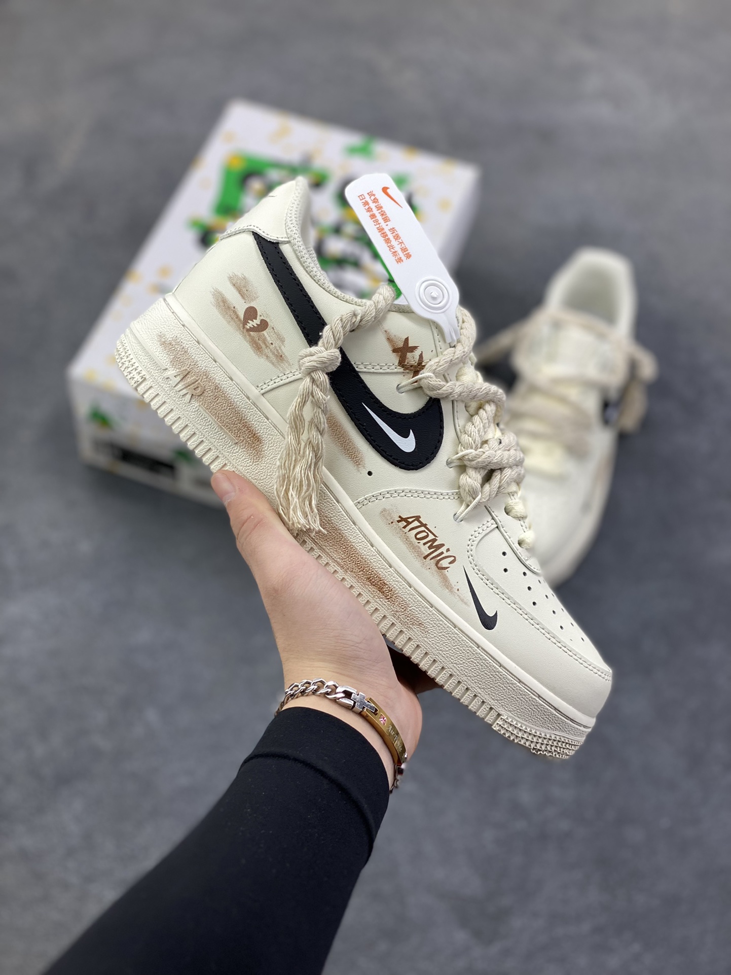 “做旧狂潮”✨订制空军一号板鞋 该定制版球鞋选用原鞋款为Nike Air Force 1\'07空军一号低帮，这是一款基于耐克Air Force 1改造的个性定制款板鞋。融入了强烈的做旧复古风，鞋身的做旧痕迹搭配“ATOMIC”字样设计，增添了街头潮流感；同时采用麻绳材质的鞋带，粗粝的质感与鞋身形成对比，极具辨识度。保留了AF1标志性的鞋型轮廓与舒适脚感，又通过做旧工艺、特殊鞋带和个性印花，打造出独一无二的复古潮流风格，适合追求小众、个性穿搭的潮流爱好者。 货号：CD6951-153 尺码：36 36.5 37.5 38 38.5 39 40 40.5 41 42 42.5 43 44 44.5 45-选品中心
