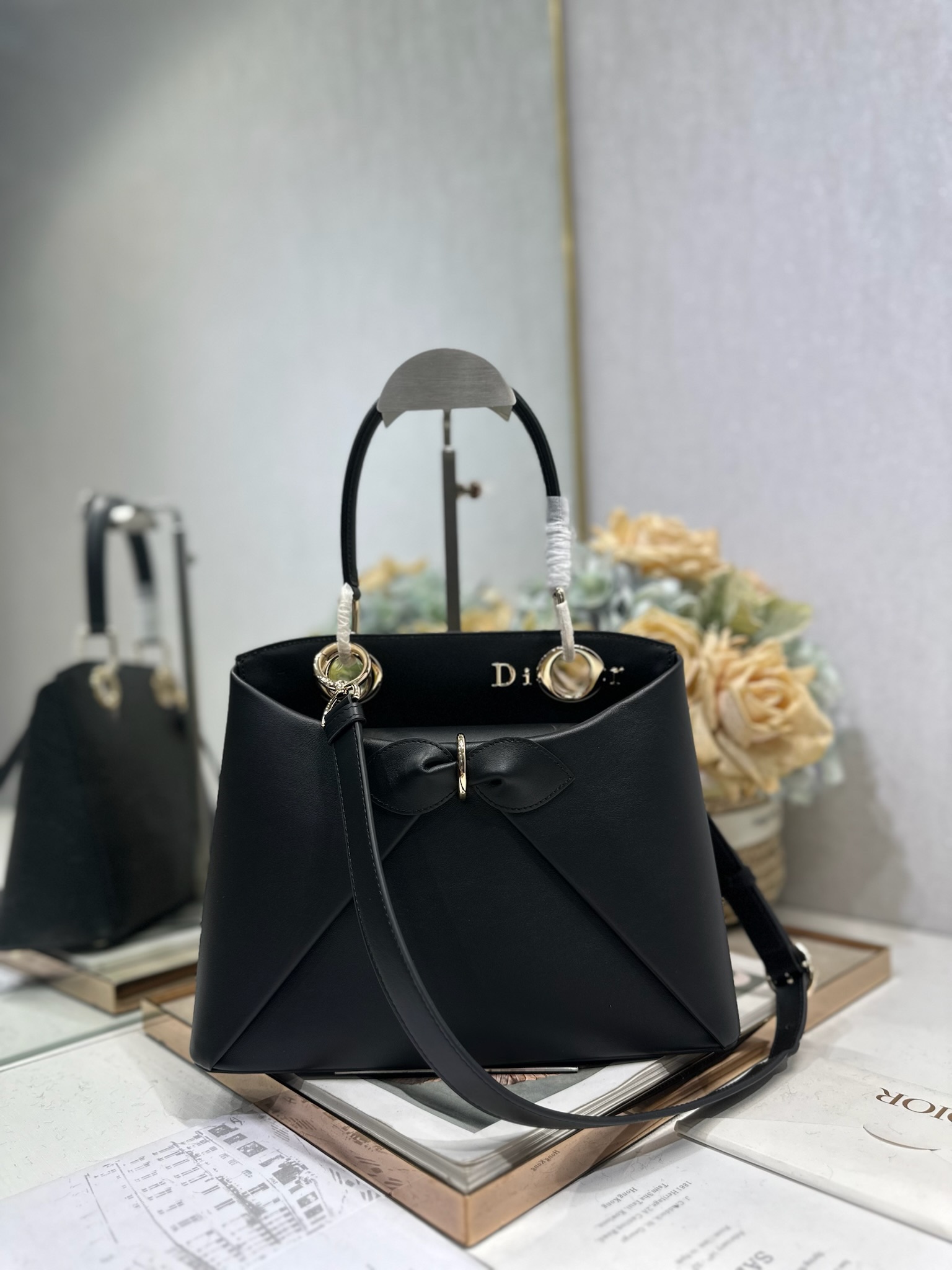 NO:771007,Dior 2026 spring and summer new product #Bowknot Handbag 'Black' has a newly designed silhouette and shape, rich colors, and is suitable for many people!  Just the right balance between exaggeration and elegance!  Its design is inspired by the Cigale dress designed by Mr. Dior ~ the three-dimensional trapezoidal body + single handle, the shape has an elegant and majestic tone. The appearance of the bag is relatively low-key, with almost no obvious big logo. Looking closer, it turns out that Anderson has integrated the Dior letter logo and the round hole of the bag handle. The bag is recognizable, and it is not ostentatious at all. The whole bag exudes a sense of quiet luxury!  It is worth mentioning that this bag is also equipped with a long leather shoulder strap. Especially when traveling, you can put on the long shoulder strap, which not only frees your hands, but also makes people relaxed and casual~ Model 0737 Size 28*10*22 (length*width*height), Dior, dior, dior19860909Dior 2026 春夏新品#蝴蝶结手提包「黑色」 新设计的轮廓与造型,配色 丰富,适配多人！在夸张与优雅之间恰到好处！它的设计灵感源于迪奥先生设计的 Cigale礼服~立体的梯形包身+单手柄,造型自带优雅大气的腔调.包包的外观比较低调,几乎没有什么明显的大Logo.离近点再看,才发现原来Anderson把Dior字母Logo和包包提手的圆孔融合到了一起. 包包既有辨识度,也完全不是张扬挂的,整体散发着那种不动声色的高级感！值得一提的是,这款包还搭配了一条皮质长肩带.尤其出门旅行的时候就可以换上长肩带,既解放了双手,还衬得人轻松又随性~ 型号0737 尺寸28*10*22（长*宽*高）,迪奥,dior,dior,Bag