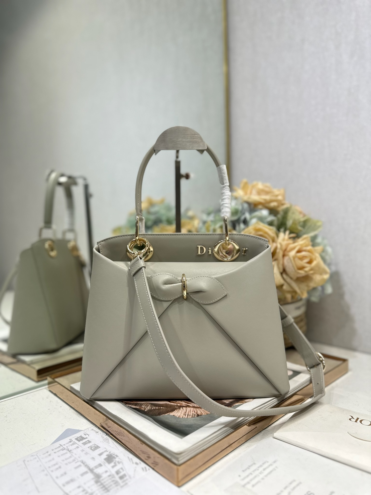 NO:771024,Dior 2026 spring and summer new product #Bowknot Handbag 'Grey' has a newly designed silhouette and shape, rich colors, and is suitable for many people!  Just the right balance between exaggeration and elegance!  Its design is inspired by the Cigale dress designed by Mr. Dior ~ the three-dimensional trapezoidal body + single handle, the shape has an elegant and majestic tone. The appearance of the bag is relatively low-key, with almost no obvious big logo. Looking closer, it turns out that Anderson has integrated the Dior letter logo and the round hole of the bag handle. The bag is recognizable, and it is not ostentatious at all. The whole bag exudes a sense of quiet luxury!  It is worth mentioning that this bag is also equipped with a long leather shoulder strap. Especially when traveling, you can put on the long shoulder strap, which not only frees your hands, but also makes people relaxed and casual~ Model 0737 Size 28*10*22 (length*width*height), Dior, dior, dior19860909Dior 2026 春夏新品#蝴蝶结手提包「灰色」 新设计的轮廓与造型,配色 丰富,适配多人！在夸张与优雅之间恰到好处！它的设计灵感源于迪奥先生设计的 Cigale礼服~立体的梯形包身+单手柄,造型自带优雅大气的腔调.包包的外观比较低调,几乎没有什么明显的大Logo.离近点再看,才发现原来Anderson把Dior字母Logo和包包提手的圆孔融合到了一起. 包包既有辨识度,也完全不是张扬挂的,整体散发着那种不动声色的高级感！值得一提的是,这款包还搭配了一条皮质长肩带.尤其出门旅行的时候就可以换上长肩带,既解放了双手,还衬得人轻松又随性~ 型号0737 尺寸28*10*22（长*宽*高）,迪奥,dior,dior,Bag