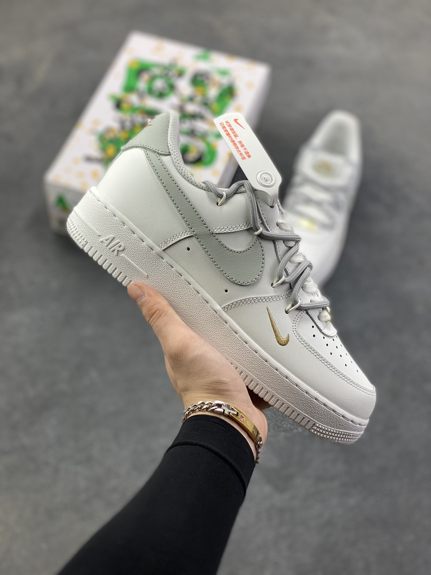 “灰金谧境”✨订制空军一号板鞋 该定制版球鞋选用原鞋款为Nike Air Force 1\’07空军一号，这是一款Nike Air Force 1 Low “白灰金双钩”鞋款，属于耐克空军一号系列的创意升级款。以白色皮革为基底，搭配浅灰色大Swoosh钩，鞋头侧面点缀金色迷你小钩，形成“大小钩”的层次设计，简约中透着精致感；鞋带采用白灰双色拼接，鞋扣处的金色细节进一步提升质感。 货号：CZ0170-106 尺码：36 36.5 37.5 38 38.5 39 40 40.5 41 42 42.5 43 44 44.5 45-选品中心