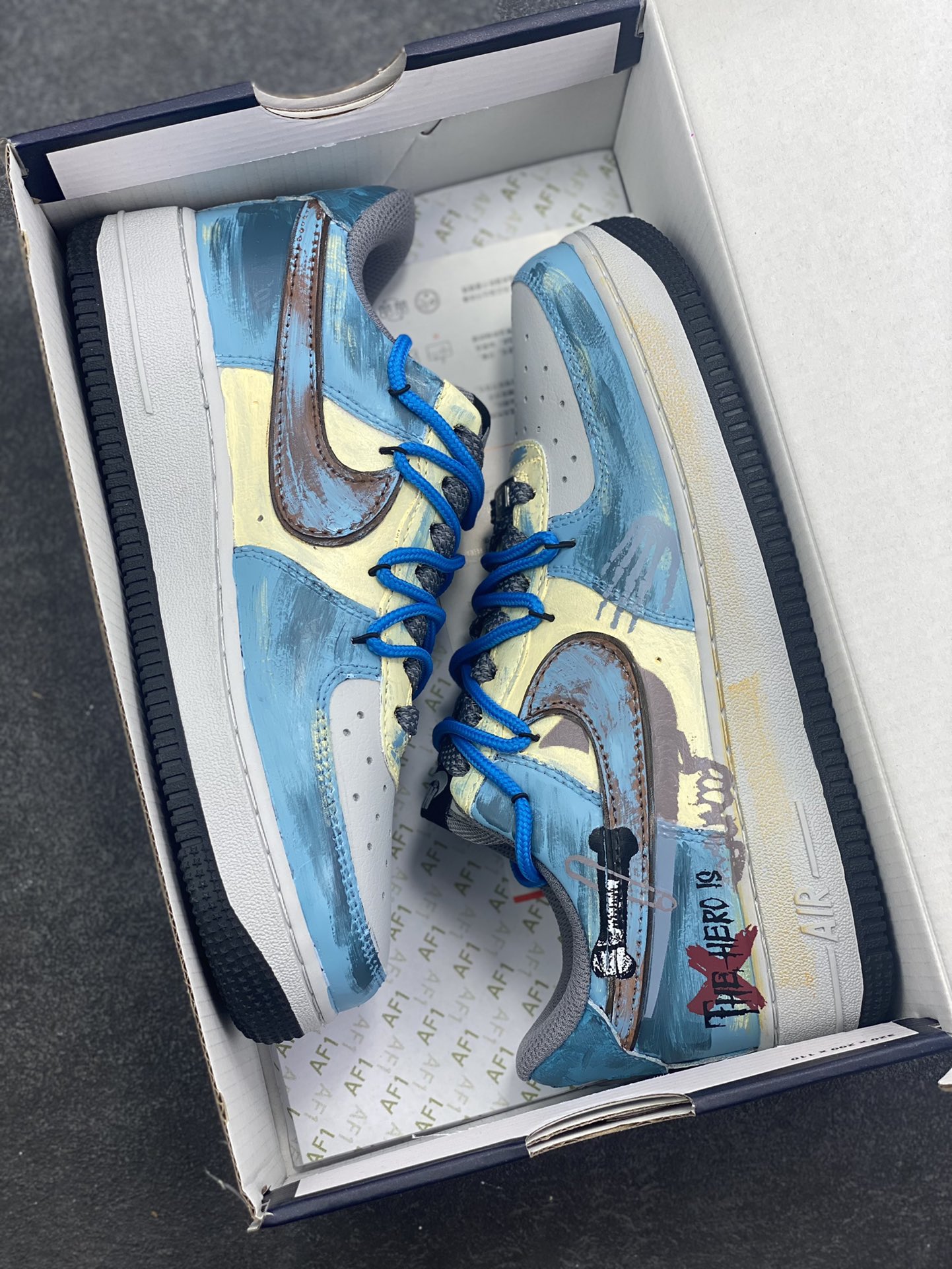 图片[9]-手绘涂鸦“雾蓝英雄”Nike Air Force 1 “Mist Blue Hero”空军一号定制板鞋 鞋身裹着一层雾感蓝灰的晕染，像清晨街景被薄雾浸软的色调，做旧肌理里藏着随性的泼墨痕迹，自带慵懒的复古滤镜；亮眼的蓝色绳状鞋带是点睛之笔，软乎乎的绳结打破了鞋身的朦胧感，添了几分街头的跳脱劲儿。鞋侧的“THE HERO”涂鸦最是灵魂——手写字体混着随性的线条，像某个少年在旧墙面上随手写下的英雄梦 货号：ZG0088-228 尺码：36 36.5 37.5 38 38.5 39 40 40.5 41 42 42.5 43 44 44.5 45-选品中心