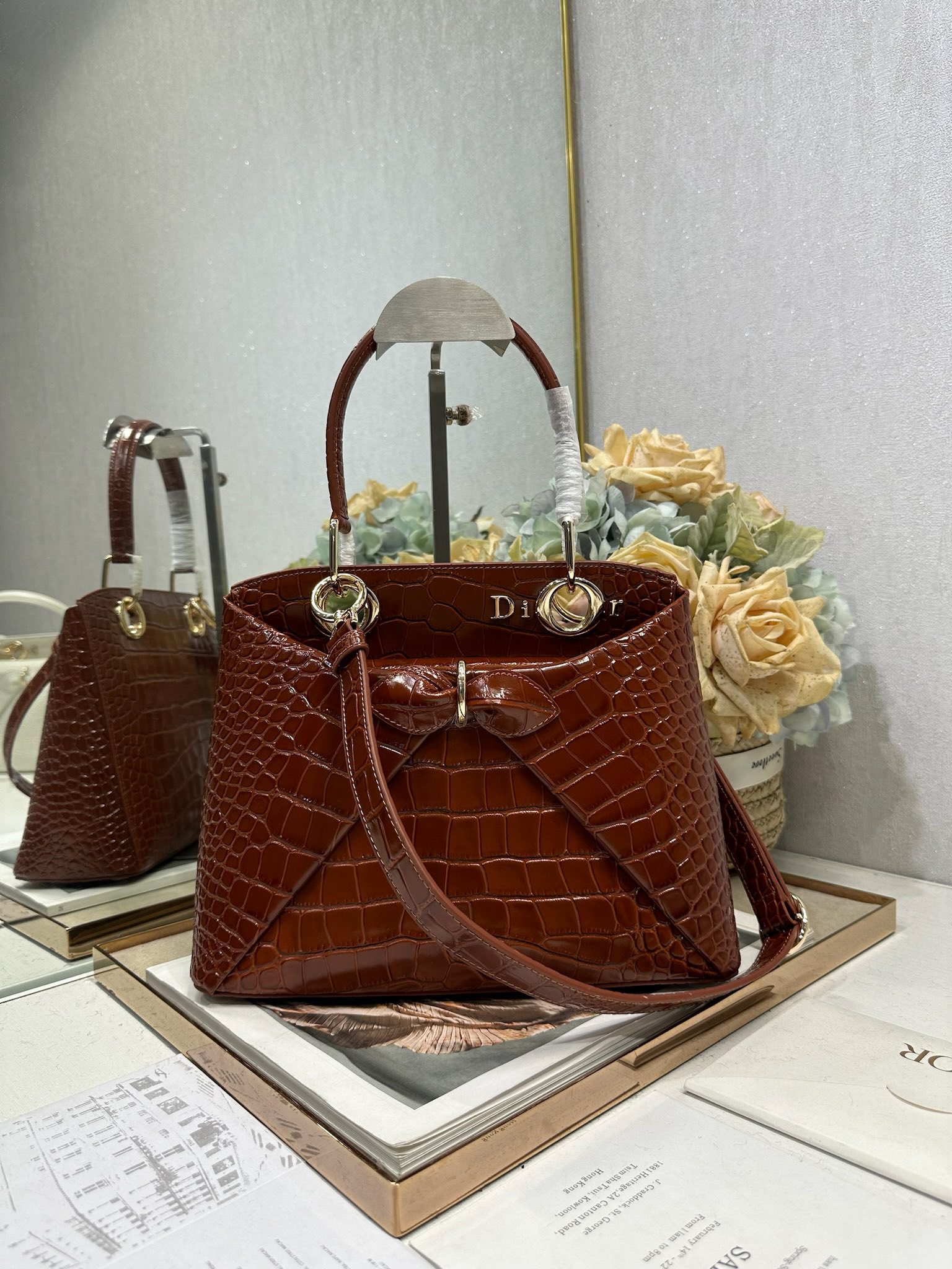 NO:771018,Dior 2026 spring and summer new product #Bowknot Handbag# Crocodile pattern 'golden brown' has a newly designed outline and shape, rich color matching, and is suitable for many people!  Just the right balance between exaggeration and elegance!  Its design is inspired by the Cigale dress designed by Mr. Dior ~ the three-dimensional trapezoidal body + single handle, the shape has an elegant and majestic tone. The appearance of the bag is relatively low-key, with almost no obvious big logo. Looking closer, it turns out that Anderson has integrated the Dior letter logo and the round hole of the bag handle. The bag is recognizable, and it is not ostentatious at all. The whole bag exudes a sense of quiet luxury!  It is worth mentioning that this bag is also equipped with a long leather shoulder strap. Especially when traveling, you can put on the long shoulder strap, which not only frees your hands, but also makes people relaxed and casual~ Model 0737 Size 28*10*22 (length*width*height), Dior, dior, dior19860909Dior 2026 春夏新品#蝴蝶结手提包#鳄鱼纹「金棕」 新设计的轮廓与造型,配色 丰富,适配多人！在夸张与优雅之间恰到好处！它的设计灵感源于迪奥先生设计的 Cigale礼服~立体的梯形包身+单手柄,造型自带优雅大气的腔调.包包的外观比较低调,几乎没有什么明显的大Logo.离近点再看,才发现原来Anderson把Dior字母Logo和包包提手的圆孔融合到了一起. 包包既有辨识度,也完全不是张扬挂的,整体散发着那种不动声色的高级感！值得一提的是,这款包还搭配了一条皮质长肩带.尤其出门旅行的时候就可以换上长肩带,既解放了双手,还衬得人轻松又随性~ 型号0737 尺寸28*10*22（长*宽*高）,迪奥,dior,dior,Bag