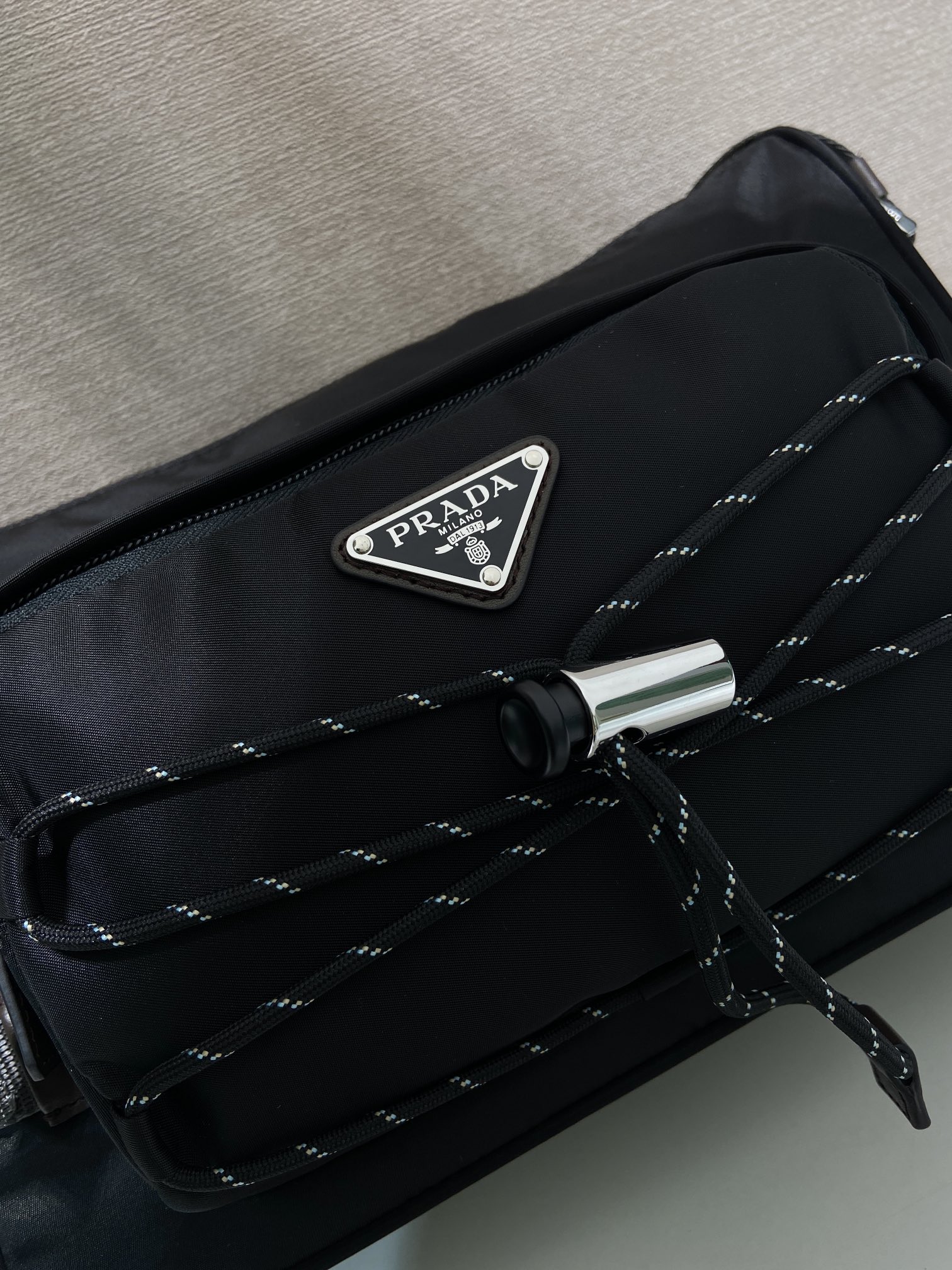 💰470🎉新款邮差包🎉2VH192新品🎉🎉
这款单肩包兼顾了功能性和装饰性，融合了都市风格和户外元素。Re-Nylon包袋设计轻巧紧凑，融入了丰富的技术细节，赋予配饰现代的运动风格。带可调节技术软线，可调编织尼龙长肩带，拉链封口。容量空间大，又是一款永久不过时爆款🎉🎉
长28x高17.5x底10cm🎉🎉🎉
