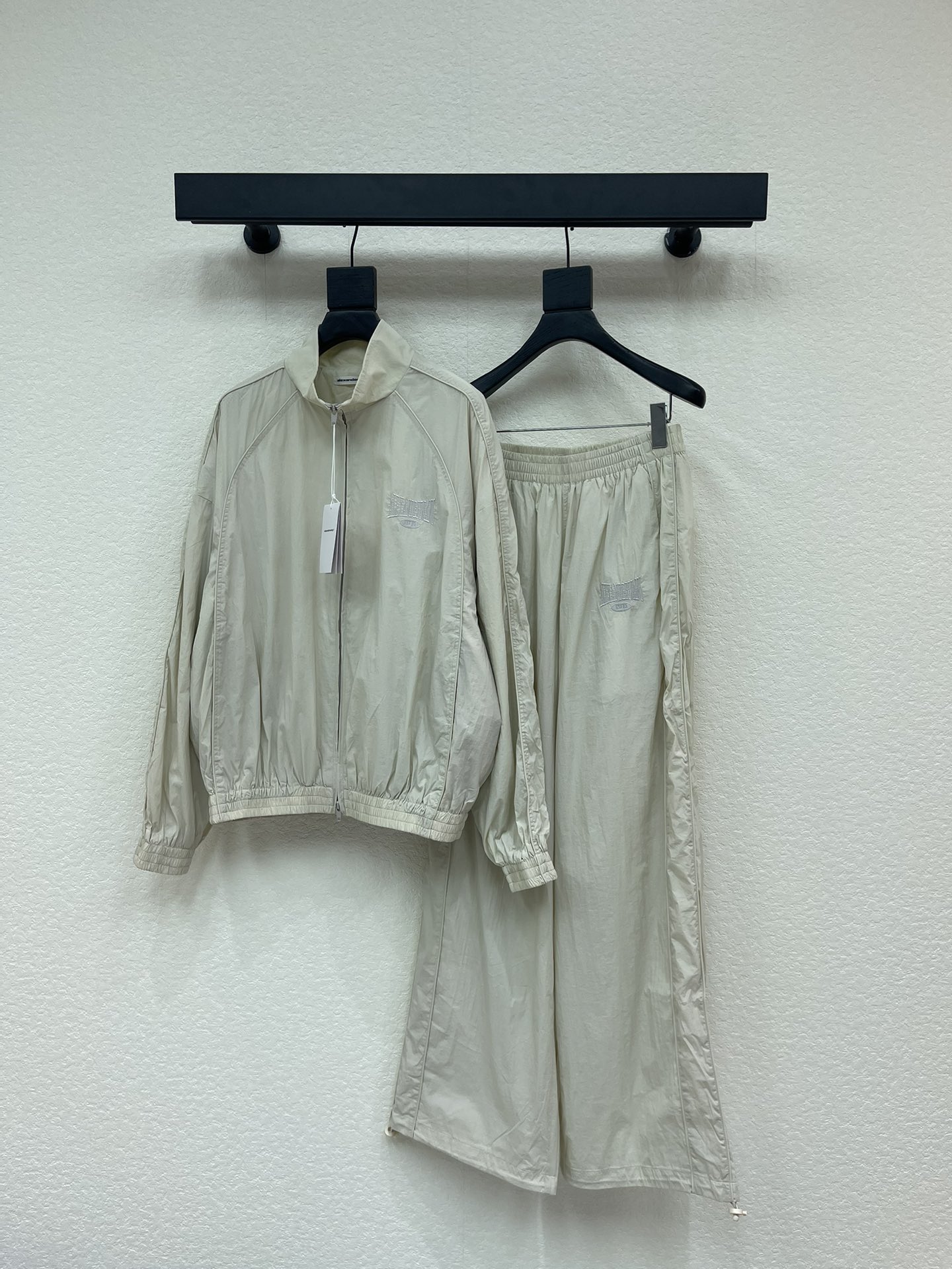 NO:658912,Alexand*r Wang 25 new autumn and winter letter embroidered stand-up collar zipper jacket + trousers suit丨Exclusive high-end version!  The milky white light assault fabric has a cool luster. The stand-up collar + full zipper design is neat and windproof. The low-key letter embroidery on the body is an AW-style cool logo. The details hide effortless high-end. The jacket has an oversize silhouette, covering the flesh without weighing down.  tall; wide-leg trousers with drawstring cuffs, casual and able to hide the shortcomings of the leg shape. Wearing it alone is a street fashionista, wearing a short vest to show off the waist instantly makes you a hot girl, layering a sweatshirt is lazy citywalk style, one set can cover all street styles in autumn and winter. SML  set,versace,hoodie,sweatshirts,jackets & coats,alexander wang19860909Alexand*r Wang 25秋冬新款字母刺绣立领拉链冲锋衣外套+长裤套装丨独家高版出品！奶白色轻薄冲锋面料自带清冷光泽,立领+全拉链设计利落又防风,衣身低调的字母刺绣是AW式的潮酷标识,细节里藏着不费力的高级.外套是oversize廓形,遮肉又不压个子；阔腿长裤配抽绳收口,随性又能藏住腿型小缺点.单穿是街头潮人,内搭短款背心露腰秒变辣妹,叠穿卫衣又是慵懒citywalk风,一套承包秋冬所有出街造型.SML 一套,,versace,hoodie,sweatshirts,jackets & coats,alexander wang,Women's clothing