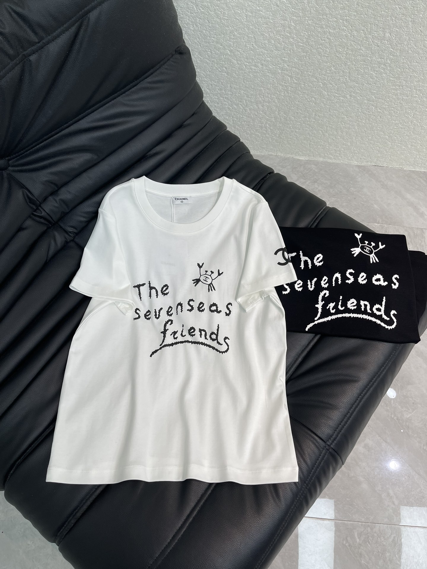 NO:657974,Chane*26 new spring and summer round neck graffiti printed short-sleeved T-shirt. Customized YB mercerized cotton material, fine texture, comfortable and breathable, regular short-sleeved cut, made of mercerized cotton material, slightly stretchy, showing a slimming visual effect, the body is centered and the printing process restores the hand-painted graffiti-like double C letter logo slogan, small crab embellishment, fun to wear, full of age reduction, black and white two-color optional, daily wear is not a bad choice, unique and fashionable.SML  A,,chanel,T-shirt,tees,t-shirt,alexander wang19860909Chane*26春夏新款圆领涂鸦印花短袖T恤.定制YB丝光全棉材质,质感细腻,舒适透气,常规短袖裁剪,采用丝光全棉材质,略带有弹力,呈现显瘦视觉效果,大身居中以印花工艺还原手绘涂鸦感双C字母徽标标语,小螃蟹点缀,玩转趣味穿搭,减龄感十足,黑白双色可选,日常穿搭不出错选择,独特且时尚.SML A,,chanel,T-shirt,tees，t-shirt,alexander wang,Women's clothing