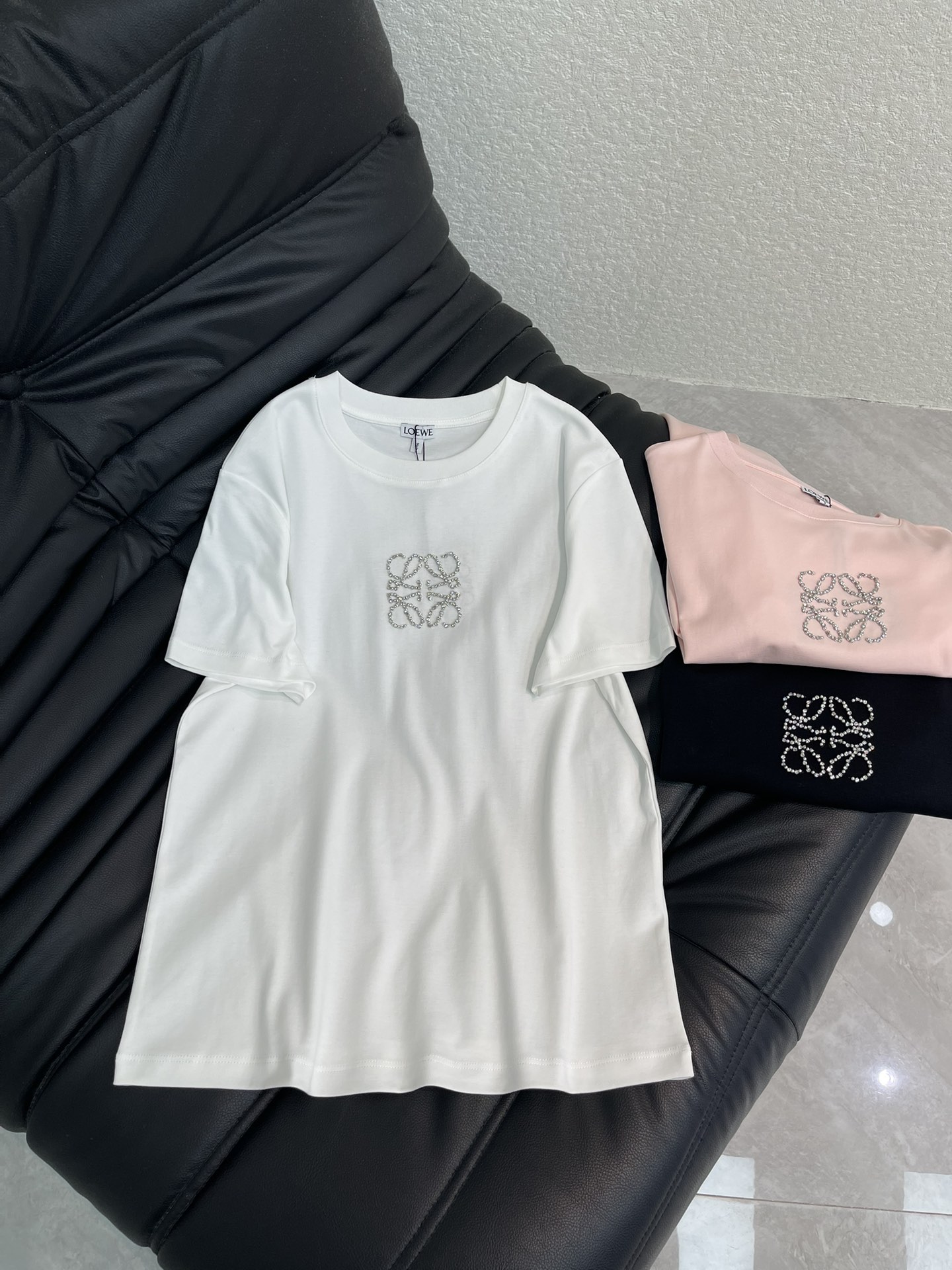 NO:658890,Loew*25 new spring and summer short-sleeved T-shirt with beaded and rhinestone letters. Customized YB mercerized cotton material, breathable and comfortable, full of texture. Regular short-sleeved T-shirt cut, with a slimming visual effect. The rhinestone beading process is used on the chest to outline the reflective totem logo to strengthen the brand identity and create a personalized style. It is refreshing and versatile for daily use. SML,, loewe, T-shirt, tees, t-shirt, alexander wang19860909Loew*25春夏新款订珠水钻字母短袖T恤.定制YB丝光全棉材质,透气舒适,质感十足,常规短袖T恤裁剪,穿搭显瘦视觉效果,胸前利用水钻钉珠工艺,勾勒出反光图腾徽标,加强品牌标识度,打造个性风格,日常清爽百搭.SML,,loewe,T-shirt,tees，t-shirt,alexander wang,Women's clothing