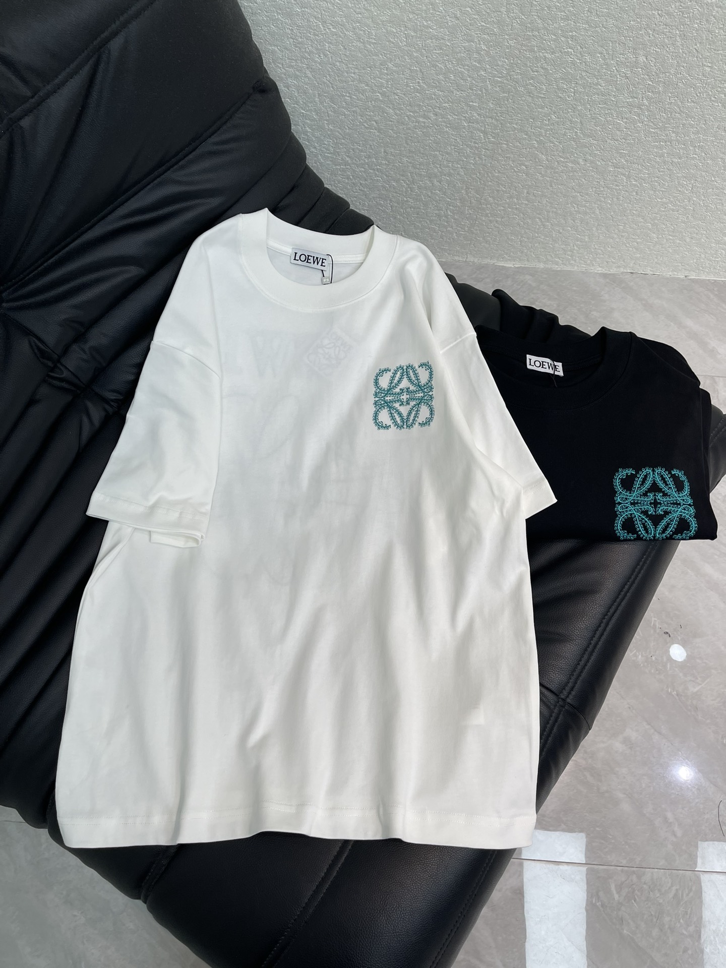 NO:664086,Loew*26 new spring and summer contrasting color logo embroidered short-sleeved T-shirt. High-weight pure cotton fabric, breathable and comfortable. The embroidery process uses thousands of floral embroidery stitches to design a square pattern composed of four entangled floral 'L's, and uses green silk thread to depict exquisite artistic fonts. Declaring the brand's design concept that has been inherited for many years!  Its eye-catching appeal is no less than any classic style, perfectly presenting a sense of fashion, high-end and luxury!  Versatile style for men and women!  S-XL A,,loewe,T-shirt,tees,t-shirt, 19860909Loew*26春夏新款撞色徽标刺绣短袖T恤.高克重纯棉面料 透气舒适.刺绣工艺以万针花饰刺绣针法设计了由四个缠绕的花体“L”组成的方形图案,以绿色丝线来描绘精致的艺术字体.宣示品牌传承多年的设计理念！其吸睛度完全不亚于任何经典款式,将时髦高级感与奢华感完美呈现眼前！百搭款 男女同款！S-XL A,,loewe,T-shirt,tees，t-shirt, ,Women's clothing