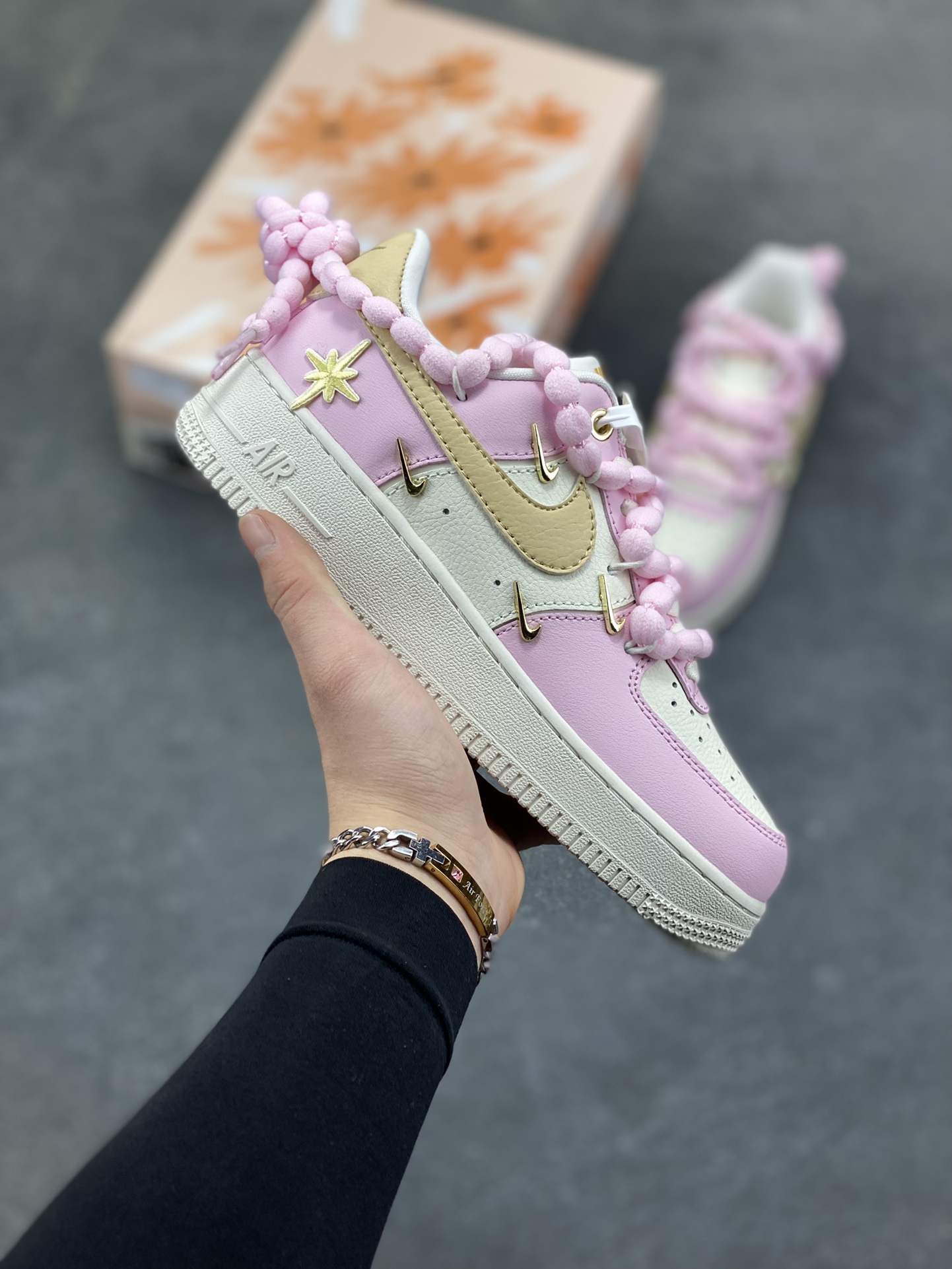 订制空军一号板鞋 该定制版球鞋选用原鞋款为Nike Air Force 1‘07空军一号，以淡粉+米白+浅卡其为主色调，搭配金色四钩装饰，鞋侧还有星星细节；图中毛绒鞋带是玩家后期搭配款，原版为常规白色鞋带。 货号：AB2574-600 尺码：35.5 36 36.5 37.5 38 38.5 39 40 40.5 41 42-选品中心
