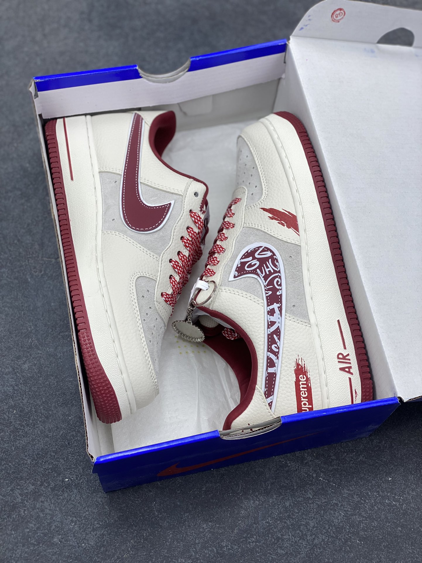 图片[9]-𝐍𝐢𝐤𝐞 𝐀𝐢𝐫 𝐅𝐨𝐫𝐜𝐞 1 𝐋𝐨𝐰 × Supreme 联名款｜街头顶流的碰撞！当空军一号的经典轮廓遇上Supreme的街头狂想，这双SY1388-019直接把潮流辨识度拉满！鞋身以米白荔枝纹皮革为主调，拼接浅灰翻毛皮打造层次质感，酒红色调从鞋舌、鞋领延伸至中底包边，成为视觉焦点。标志性Swoosh覆盖满印涂鸦花纹，鞋侧的Supreme红标醒目又张扬，鞋头的泼墨红纹更是细节感拉满，将街头艺术与经典鞋型的融合玩到极致。经典低帮AF1鞋型兼顾百搭与脚感，软弹Air气垫加持日常行走毫无压力，不管是搭配工装裤还是运动束脚裤，都能轻松穿出街头潮酷范，堪称潮人鞋柜里的“硬通货”！-选品中心