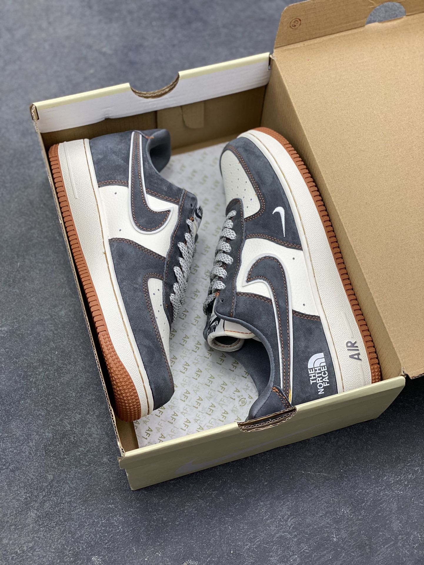 图片[9]-Nike Air Force 1 Low x The North Face 联名款｜硬核潮搭新标杆！当经典空军一号遇上户外王者北面，这双SS1979-005配色的Air Force 1 Low直接把街头潮流与户外机能风焊死在鞋面上！深灰磨砂麂皮碰撞米白皮革，橙棕车线勾勒出硬朗的户外质感，鞋侧双品牌标识强强联手，既有AF1的复古板鞋基因，又融入The North Face的户外硬核气场。生胶外底搭配Air气垫，踩屎感拉满的同时，复古氛围直接拉到顶点。不管是搭配工装裤走街头户外风，还是配牛仔裤搭休闲造型，这双鞋都能成为造型的点睛之笔，潮人鞋柜里的“王炸款”非它莫属！-选品中心