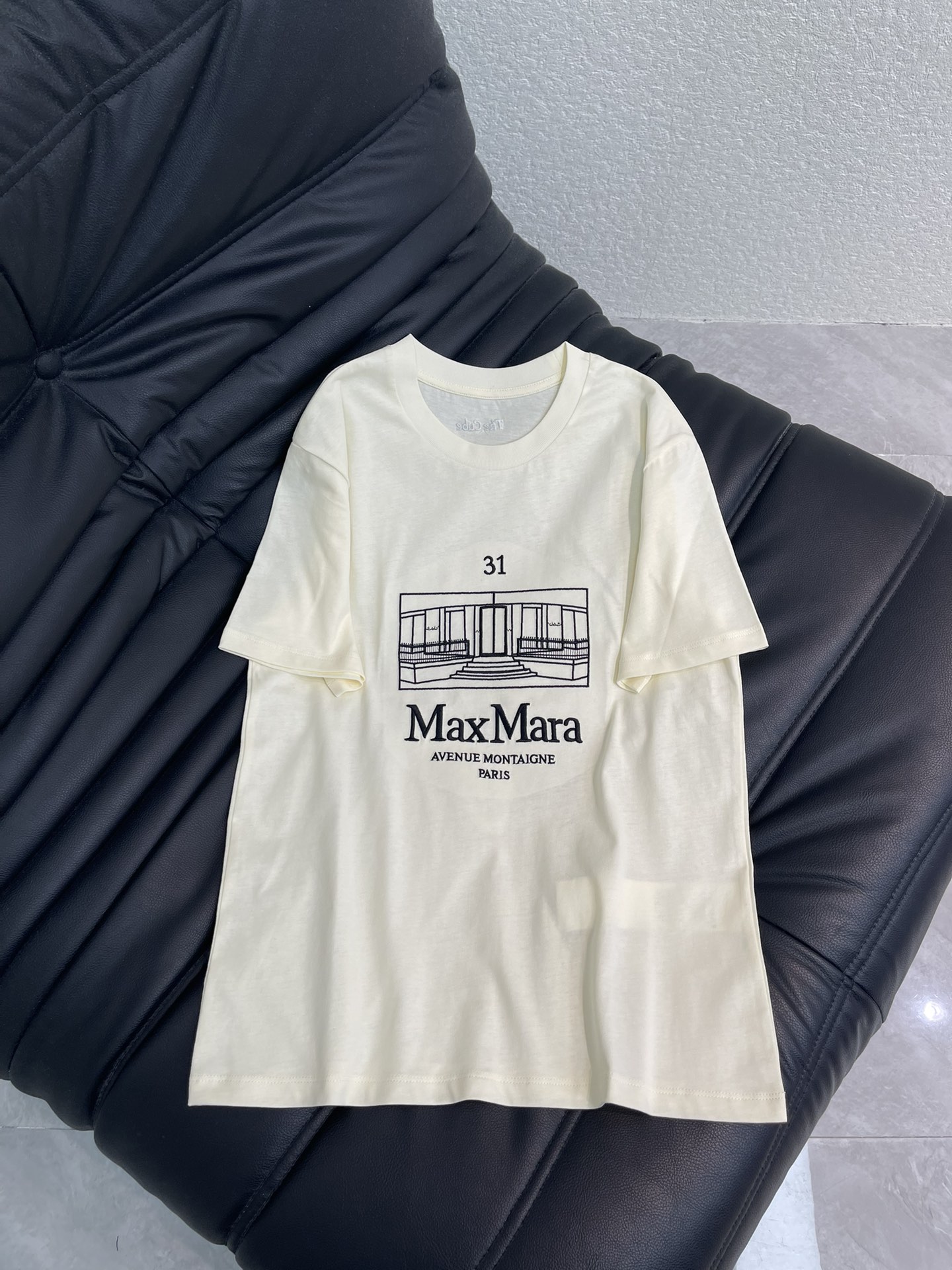 NO:667579,Weekend  MaxMar*26 new spring and summer short-sleeved T-shirt with embroidered pattern. The beige body is matched with embroidered black architectural lines, which restores the classic silhouette of the MaxMara store at No. 31 Avenue Montaigne in Paris. The brand logo and place name text are arranged at random, and the French light luxury style is revealed in simplicity.  The back embroidery becomes the visual focus. MaxMara classic store architectural print short sleeves, minimalist lines outline the brand landmark, the number '31' echoes the brand name, and the black print is more exquisite on the beige fabric. Wearing the brand's classic elements on the body, low-key highlights the light luxury taste. SML  AA,,T-shirt,tees,t-shirt, 19860909Weekend MaxMar*26春夏新款刺绣图案短袖T恤.米黄色衣身搭配刺绣黑色建筑线条,还原巴黎蒙田大道31号MaxMara门店经典轮廓,品牌标识与地名文字错落排布,简约中透着法式轻奢格调,后背刺绣成为视觉焦点,MaxMara经典门店建筑印花短袖,极简线条勾勒品牌地标,数字“31”与品牌名呼应,黑色印花在米黄面料上更显精致,把品牌经典元素穿在身上,低调彰显轻奢品味.SML AA,,T-shirt,tees，t-shirt, ,Women's clothing