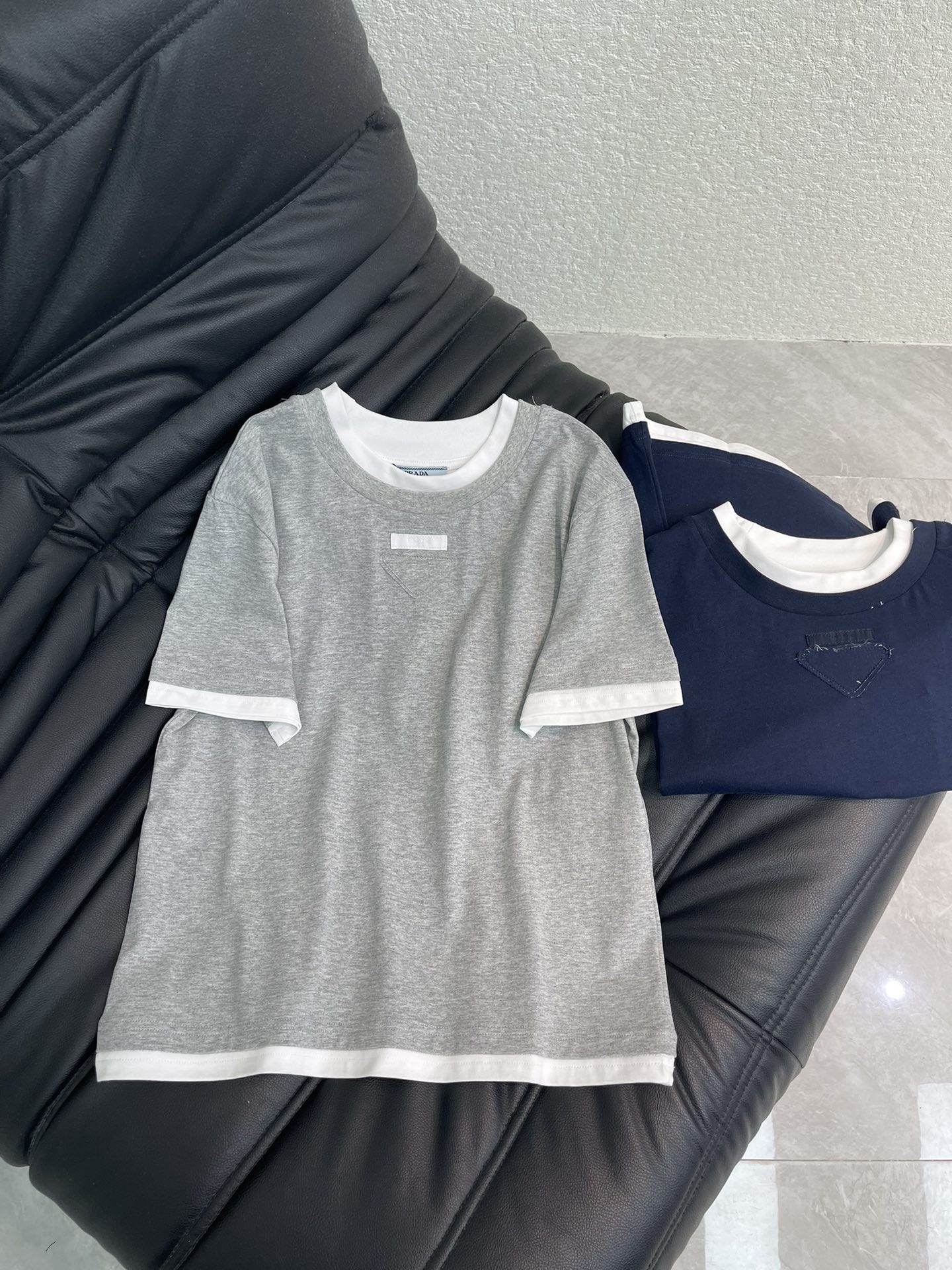 NO:667568,Prad*26 new spring and summer contrasting fake two-piece short-sleeved T-shirt with triangle logo. Customized YB twill cotton material, breathable and comfortable, full of texture, regular short-sleeved shirt cut, using contrasting color treatment, white thread binding on the collar, cuffs and hem, superimposed on the body to form a contrasting fake two-piece stacking effect, triangle logo decoration on the chest, distinct layers, creating a fashionable style, trendy and fashionable. SML,, prada, T-shirt, tees, t-shirt,  19860909Prad*26春夏新款撞色假两件三角标短袖T恤.定制YB斜纹全棉材质,透气舒适,质感十足,常规短袖恤剪裁,利用撞色处理,领口袖口和下摆白色螺纹包边,叠加大身形成撞色的假两件叠穿效果,胸口三角徽标装饰,层次分明,打造时尚风格,穿搭潮流时髦.SML,,prada,T-shirt,tees，t-shirt, ,Women's clothing