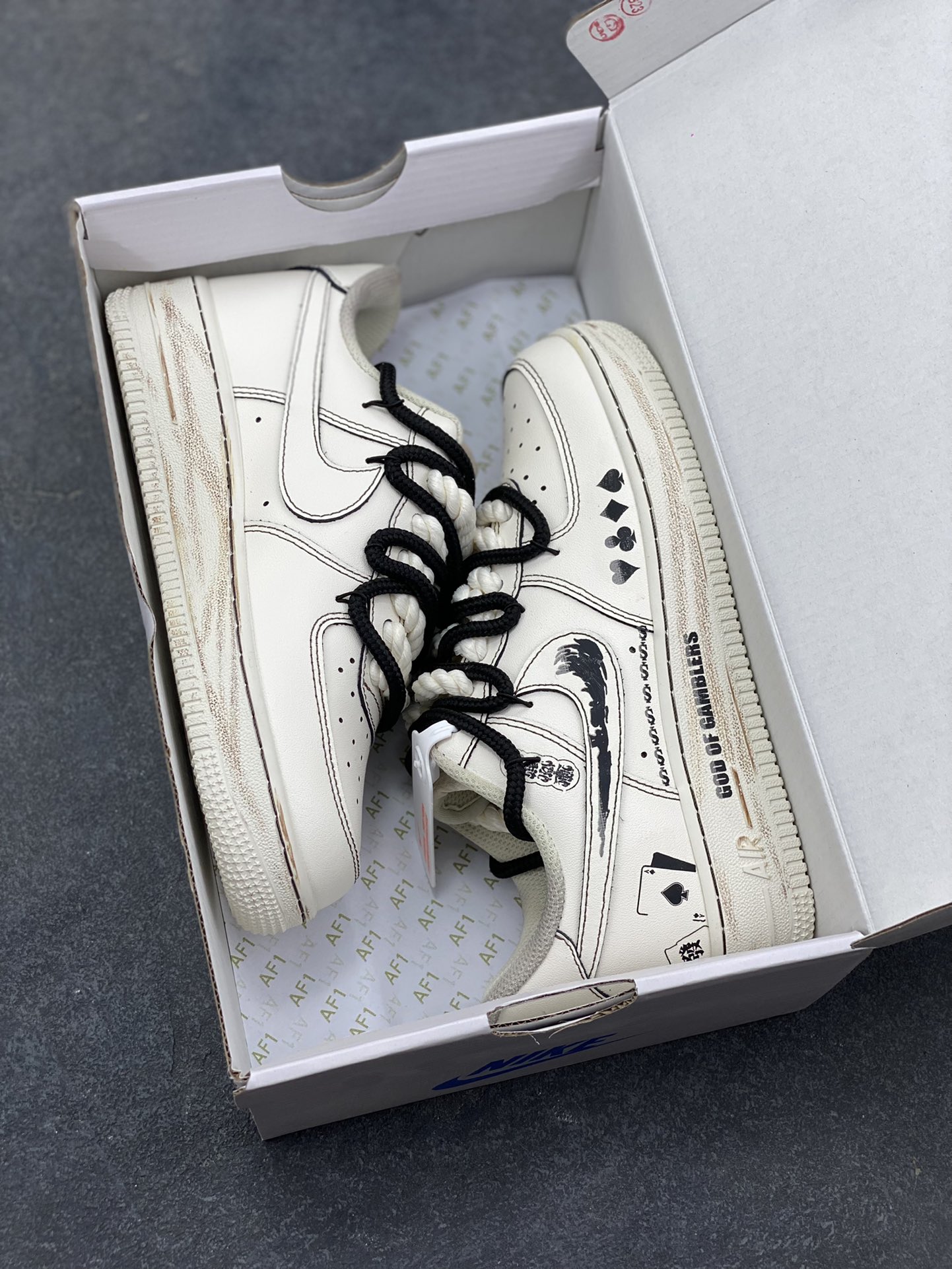 图片[9]-手绘涂鸦“赌神底牌”Nike Air Force 1 “GOD OF GAMBLERS”空军一号定制板鞋 米白基底像未掀开的牌面，黑调涂鸦勾勒出扑克牌花色、“GOD OF GAMBLERS” 字样，搭配黑白绳结鞋带，自带复古港风的凌厉气场；做旧质感与手绘笔触交织，让每一处设计都像藏着 “底牌” 的惊喜，是把 “赌局氛围感” 穿在脚上的潮酷单品 货号：315122-313 尺码： 36 36.5 37.5 38 38.5 39 40 40.5 41 42 42.5 43 44 44.5 45-选品中心