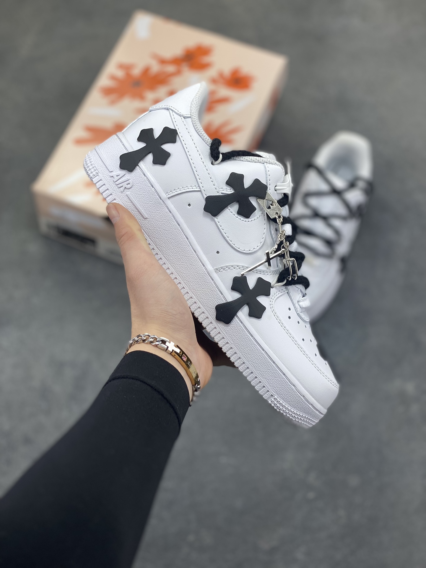 “十字星芒”✨订制空军一号板鞋 该定制版球鞋选用原鞋款为Nike Air Force 1‘07空军一号，鞋身大面积点缀黑色克罗心风格十字花元素，黑白撞色形成强烈视觉冲击，成为最亮眼的设计标识。替换成黑色粗鞋带，搭配金属十字挂饰等配饰，打破了纯白空军一号的简约感，强化了定制的独特性。 货号：CW2288-111 尺码： 36 36.5 37.5 38 38.5 39 40 40.5 41 42 42.5 43 44 44.5 45-选品中心