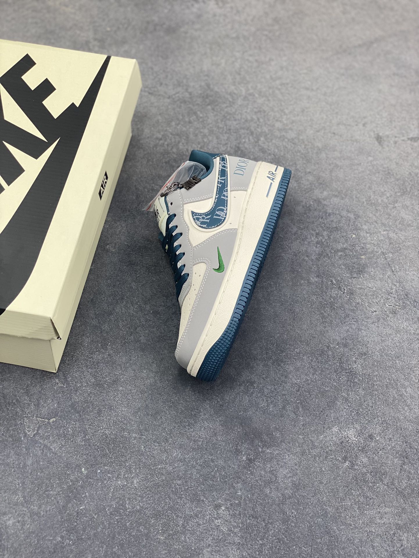 图片[7]-格调碰撞，经典新生！当Nike Air Force 1的街头基因遇上Dior的高奢美学，这双Air Force 1 Low DD1928-313完成了一次惊艳的风格跨界。高级灰调为主的鞋身，搭配深海蓝的撞色点缀，皮质拼接的质感扑面而来。Swoosh标志上的Dior字母印花、鞋侧的品牌标识，将奢华细节融入经典鞋型，小勾设计更是暗藏巧思。米白中底搭配蓝调外底，延续AF1的复古轮廓，又赋予了全新的视觉层次。无论是日常出街的随性搭配，还是打造高街奢潮造型，这双鞋都能成为造型的点睛之笔，让经典鞋款在奢潮融合中焕发全新魅力。-选品中心