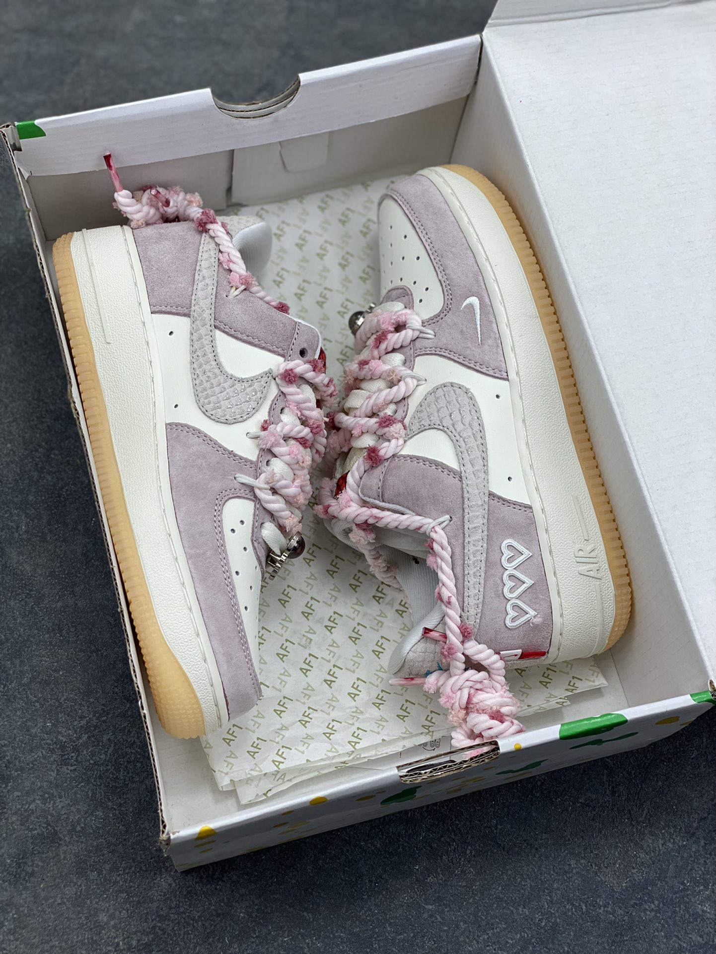 图片[9]-“芋泥告白”订制空军一号板鞋 该定制版球鞋选用原鞋款为Nike Air Force 1‘07空军一号，鞋面选用芋泥粉麂皮与米白皮革拼接，材质对比营造出细腻的质感，芋泥粉＋米白的低饱和配色搭配生胶底，复古感拉满。鞋侧后跟有镂空爱心刺绣，鞋带换成粉灰混色粗织绳带并搭配金属扣，鞋头还点缀了迷你Swoosh，爱心元素的融入让整体设计更具少女感与独特性。 货号：FA5066-111-选品中心