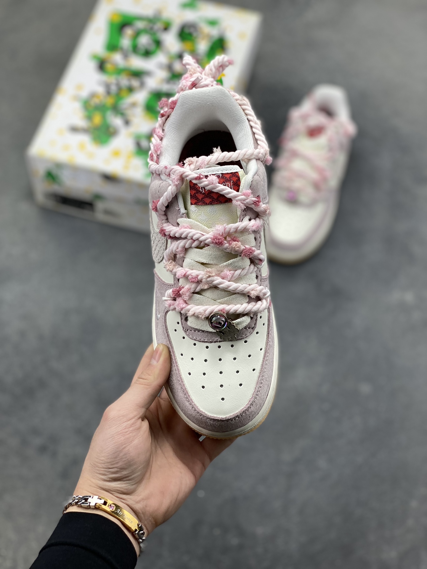 图片[2]-“芋泥告白”订制空军一号板鞋 该定制版球鞋选用原鞋款为Nike Air Force 1‘07空军一号，鞋面选用芋泥粉麂皮与米白皮革拼接，材质对比营造出细腻的质感，芋泥粉＋米白的低饱和配色搭配生胶底，复古感拉满。鞋侧后跟有镂空爱心刺绣，鞋带换成粉灰混色粗织绳带并搭配金属扣，鞋头还点缀了迷你Swoosh，爱心元素的融入让整体设计更具少女感与独特性。 货号：FA5066-111-选品中心