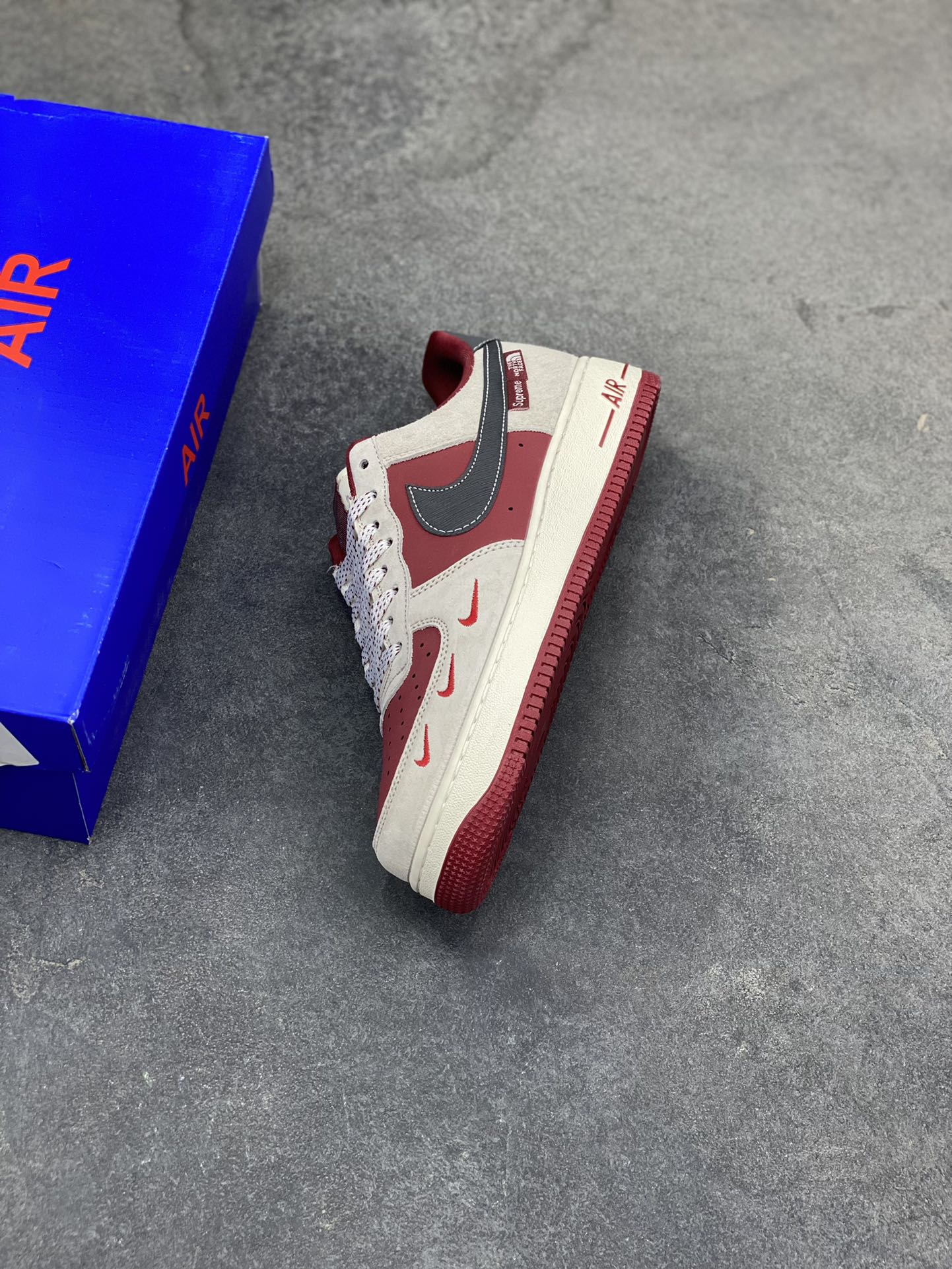 图片[7]-Nike Air Force 1 Low x Supreme x The North Face 三方联名酒红灰配色，直接把街头潮流与户外机能风焊死在鞋面上！酒红麂皮碰撞浅灰磨砂质感，鞋身多道迷你红勾打破常规，侧边Supreme×TNF织标强强联手，藏青Swoosh做旧处理更添复古韵味。白红中底刻字“Air”细节拉满，酒红外底踩出吸睛步调，挂饰吊坠更是把联名仪式感拉满。经典AF1鞋型加持，不管是搭配工装裤还是牛仔潮搭，都能轻松拿捏高阶街头感，这双SY1388-014绝对是潮人鞋柜里的收藏级狠货！-选品中心