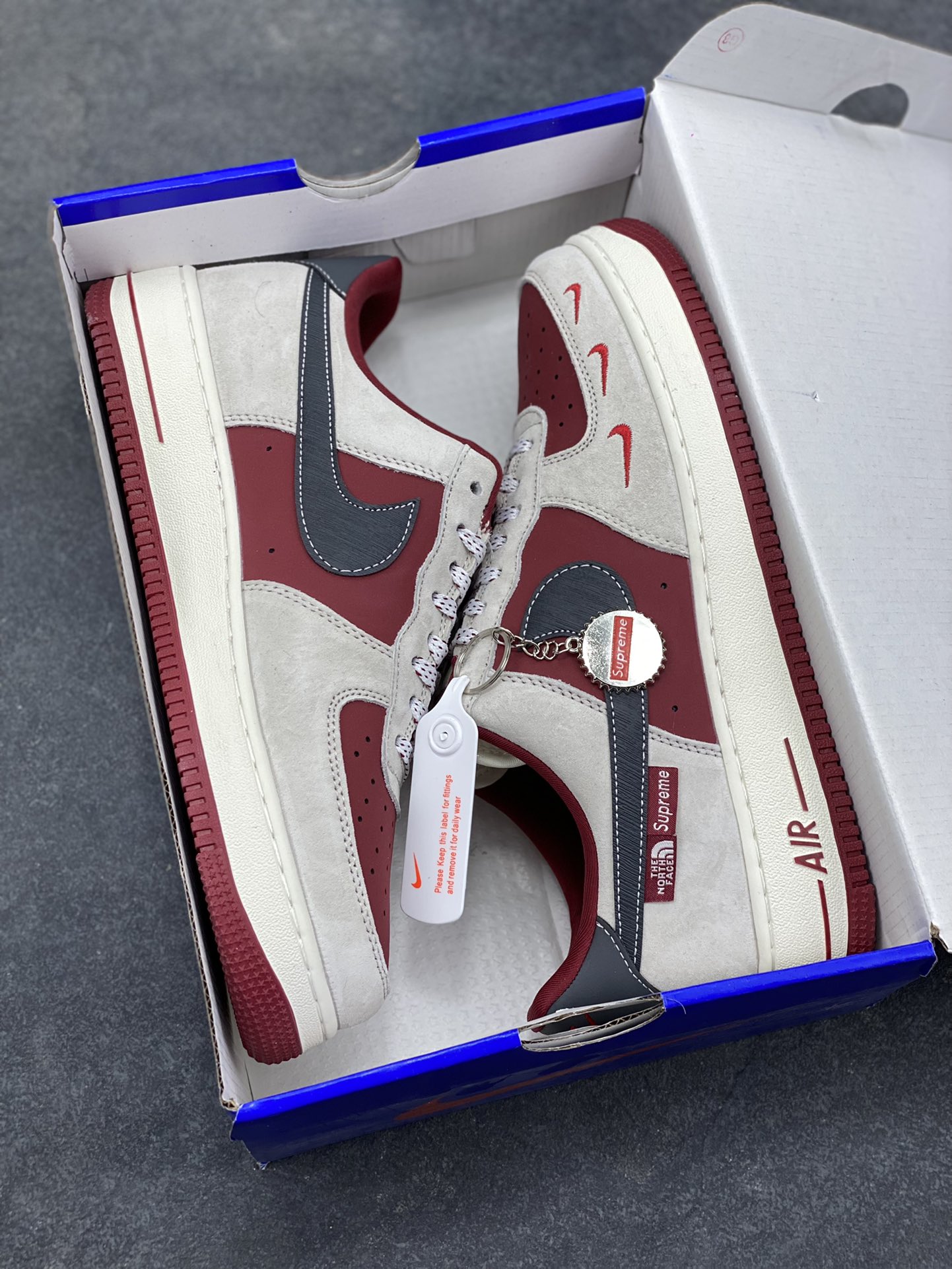 图片[9]-Nike Air Force 1 Low x Supreme x The North Face 三方联名酒红灰配色，直接把街头潮流与户外机能风焊死在鞋面上！酒红麂皮碰撞浅灰磨砂质感，鞋身多道迷你红勾打破常规，侧边Supreme×TNF织标强强联手，藏青Swoosh做旧处理更添复古韵味。白红中底刻字“Air”细节拉满，酒红外底踩出吸睛步调，挂饰吊坠更是把联名仪式感拉满。经典AF1鞋型加持，不管是搭配工装裤还是牛仔潮搭，都能轻松拿捏高阶街头感，这双SY1388-014绝对是潮人鞋柜里的收藏级狠货！-选品中心