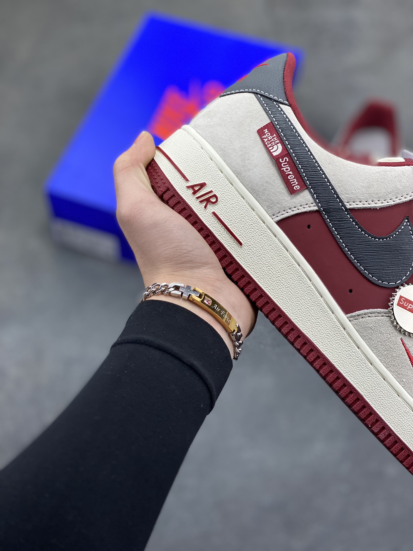 图片[6]-Nike Air Force 1 Low x Supreme x The North Face 三方联名酒红灰配色，直接把街头潮流与户外机能风焊死在鞋面上！酒红麂皮碰撞浅灰磨砂质感，鞋身多道迷你红勾打破常规，侧边Supreme×TNF织标强强联手，藏青Swoosh做旧处理更添复古韵味。白红中底刻字“Air”细节拉满，酒红外底踩出吸睛步调，挂饰吊坠更是把联名仪式感拉满。经典AF1鞋型加持，不管是搭配工装裤还是牛仔潮搭，都能轻松拿捏高阶街头感，这双SY1388-014绝对是潮人鞋柜里的收藏级狠货！-选品中心