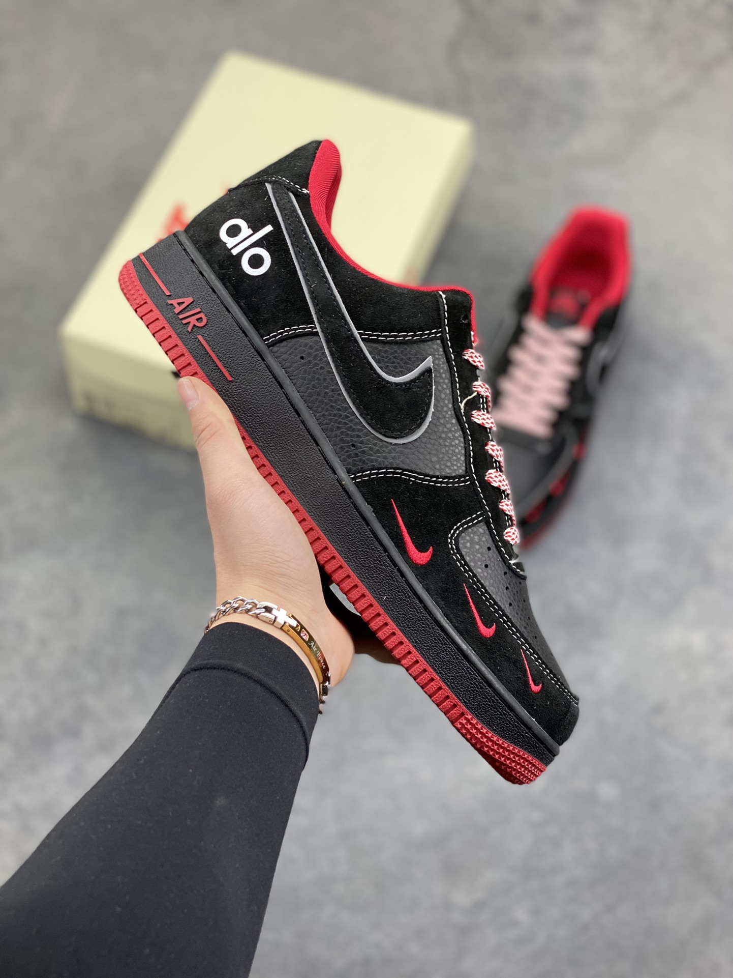 黑红格调，经典焕新｜Nike Air Force 1 Low alo联名款 当经典的Air Force 1 Low遇上alo的潮流基因，黑红撞色瞬间点燃街头气场。 全黑荔枝纹皮革鞋身质感拉满，鞋头点缀的红色迷你Swoosh暗藏巧思，鞋侧银线勾边的大勾在低调中透出锋芒，后跟的“alo”标识更是联名身份的亮眼注脚。红色鞋舌、鞋领包边与外底纹路形成视觉呼应，搭配红白编织鞋带，细节处尽显设计巧思。 Air气垫加持的经典中底，刻有红色“AIR”字样，延续AF1的舒适脚感与街头底蕴。黑红配色永不过时，无论是日常穿搭还是街头炸街，这双SS1979-009都能让你轻松拿捏潮流腔调，成为足下焦点。-选品中心