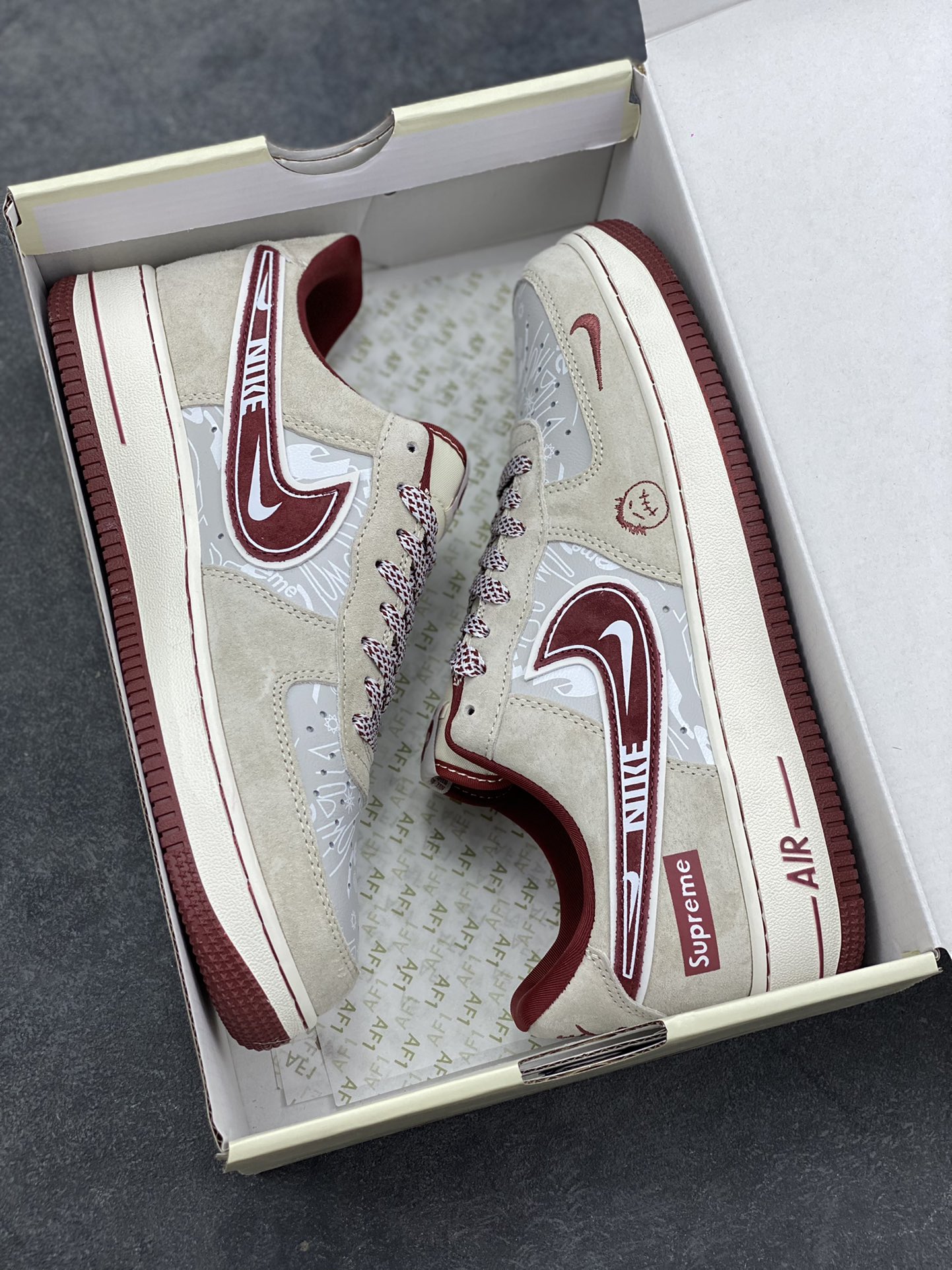 图片[9]-解构潮范，低帮新绎｜Nike Air Force 1 Low x Supreme联名款！当Nike Air Force 1 Low的经典街头底蕴碰撞Supreme的硬核潮牌基因，这双SS1979-012联名款成为街头潮流跨界的又一重磅之作，将复古板鞋的魅力与潮牌的个性表达融合到极致。 鞋身以浅米翻毛皮革为主调，酒红色饰条勾勒出利落的轮廓线条，材质的细腻质感与色彩的撞色搭配，瞬间拉满视觉层次。解构主义设计的双层Swoosh打破常规，酒红主Swoosh叠搭白色细勾，侧边印刻的“NIKE”与Supreme方块标识相互呼应，鞋舌处的编织鞋带、鞋身的涂鸦风暗纹，每一处细节都暗藏联名的巧思。鞋侧的小勾刺绣、中底的“Air”字样与酒红外底的组合，延续了Air Force 1 Low的经典轮廓，又为鞋款注入了Supreme标志性的潮酷灵魂。浅米中底搭配酒红外底，兼顾了复古脚感与潮流视觉，让这双联名款既能适配街头工装风穿搭，也能融入高街休闲造型。无论是潮牌爱好者的收藏清单，还是日常出街的吸睛选择，这双Nike Air Force 1 Low x Supreme都能以解构潮范的独特气质，让你轻松成为街头焦点。-选品中心
