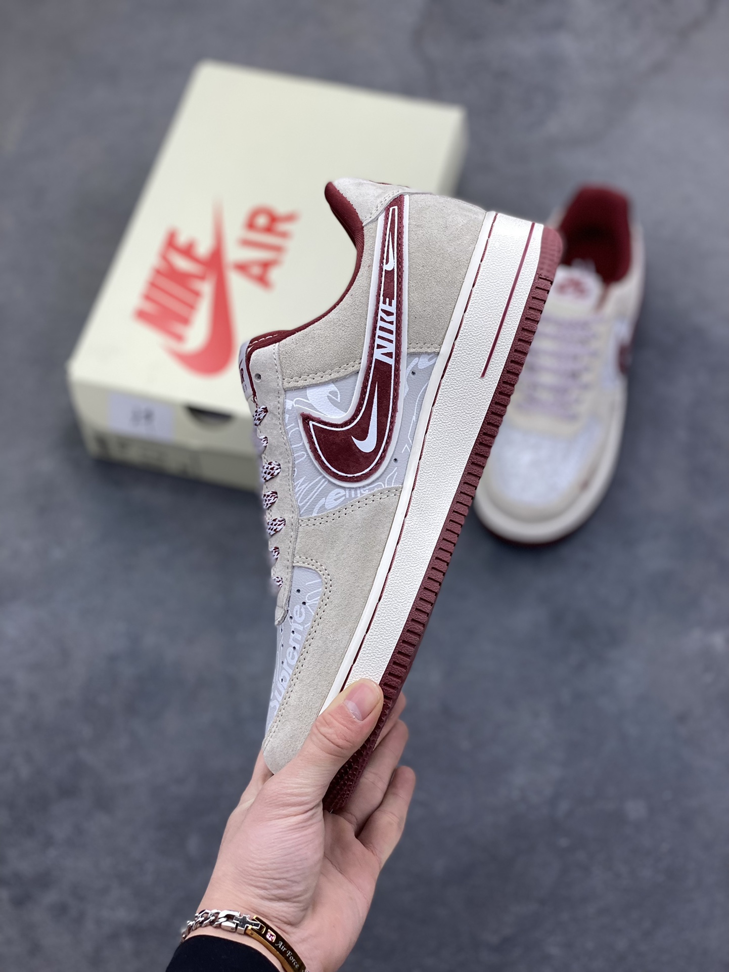 图片[3]-解构潮范，低帮新绎｜Nike Air Force 1 Low x Supreme联名款！当Nike Air Force 1 Low的经典街头底蕴碰撞Supreme的硬核潮牌基因，这双SS1979-012联名款成为街头潮流跨界的又一重磅之作，将复古板鞋的魅力与潮牌的个性表达融合到极致。 鞋身以浅米翻毛皮革为主调，酒红色饰条勾勒出利落的轮廓线条，材质的细腻质感与色彩的撞色搭配，瞬间拉满视觉层次。解构主义设计的双层Swoosh打破常规，酒红主Swoosh叠搭白色细勾，侧边印刻的“NIKE”与Supreme方块标识相互呼应，鞋舌处的编织鞋带、鞋身的涂鸦风暗纹，每一处细节都暗藏联名的巧思。鞋侧的小勾刺绣、中底的“Air”字样与酒红外底的组合，延续了Air Force 1 Low的经典轮廓，又为鞋款注入了Supreme标志性的潮酷灵魂。浅米中底搭配酒红外底，兼顾了复古脚感与潮流视觉，让这双联名款既能适配街头工装风穿搭，也能融入高街休闲造型。无论是潮牌爱好者的收藏清单，还是日常出街的吸睛选择，这双Nike Air Force 1 Low x Supreme都能以解构潮范的独特气质，让你轻松成为街头焦点。-选品中心