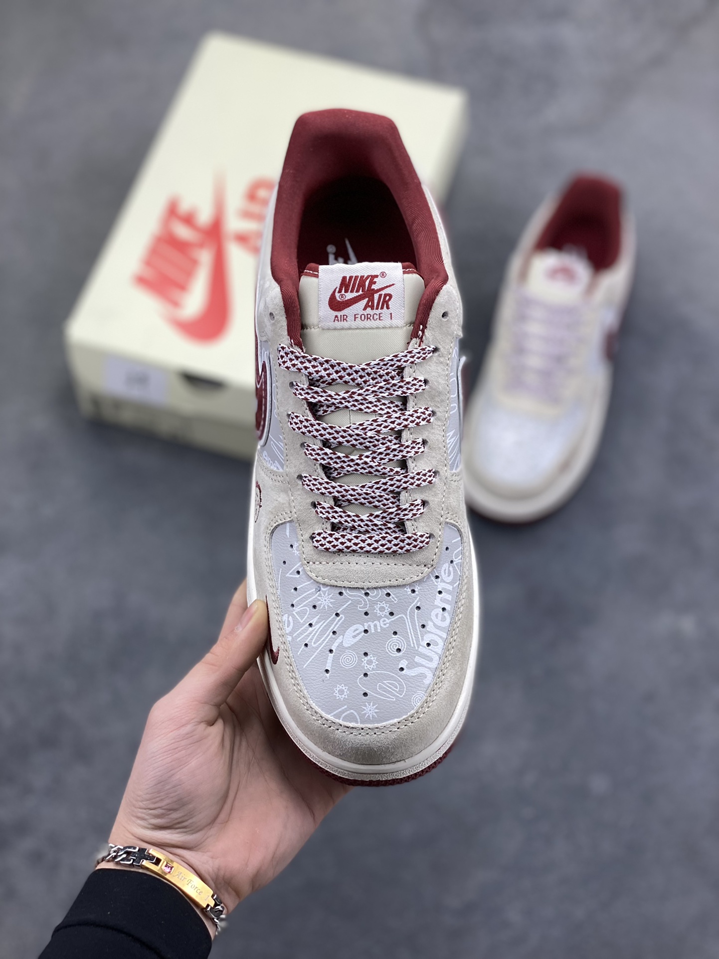 图片[2]-解构潮范，低帮新绎｜Nike Air Force 1 Low x Supreme联名款！当Nike Air Force 1 Low的经典街头底蕴碰撞Supreme的硬核潮牌基因，这双SS1979-012联名款成为街头潮流跨界的又一重磅之作，将复古板鞋的魅力与潮牌的个性表达融合到极致。 鞋身以浅米翻毛皮革为主调，酒红色饰条勾勒出利落的轮廓线条，材质的细腻质感与色彩的撞色搭配，瞬间拉满视觉层次。解构主义设计的双层Swoosh打破常规，酒红主Swoosh叠搭白色细勾，侧边印刻的“NIKE”与Supreme方块标识相互呼应，鞋舌处的编织鞋带、鞋身的涂鸦风暗纹，每一处细节都暗藏联名的巧思。鞋侧的小勾刺绣、中底的“Air”字样与酒红外底的组合，延续了Air Force 1 Low的经典轮廓，又为鞋款注入了Supreme标志性的潮酷灵魂。浅米中底搭配酒红外底，兼顾了复古脚感与潮流视觉，让这双联名款既能适配街头工装风穿搭，也能融入高街休闲造型。无论是潮牌爱好者的收藏清单，还是日常出街的吸睛选择，这双Nike Air Force 1 Low x Supreme都能以解构潮范的独特气质，让你轻松成为街头焦点。-选品中心