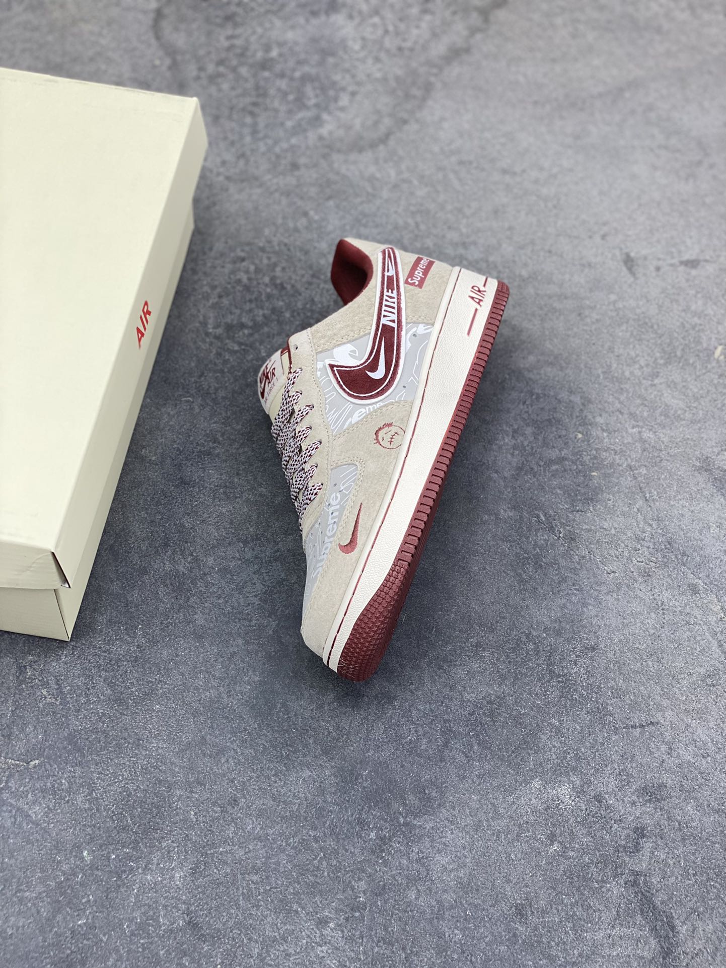 图片[7]-解构潮范，低帮新绎｜Nike Air Force 1 Low x Supreme联名款！当Nike Air Force 1 Low的经典街头底蕴碰撞Supreme的硬核潮牌基因，这双SS1979-012联名款成为街头潮流跨界的又一重磅之作，将复古板鞋的魅力与潮牌的个性表达融合到极致。 鞋身以浅米翻毛皮革为主调，酒红色饰条勾勒出利落的轮廓线条，材质的细腻质感与色彩的撞色搭配，瞬间拉满视觉层次。解构主义设计的双层Swoosh打破常规，酒红主Swoosh叠搭白色细勾，侧边印刻的“NIKE”与Supreme方块标识相互呼应，鞋舌处的编织鞋带、鞋身的涂鸦风暗纹，每一处细节都暗藏联名的巧思。鞋侧的小勾刺绣、中底的“Air”字样与酒红外底的组合，延续了Air Force 1 Low的经典轮廓，又为鞋款注入了Supreme标志性的潮酷灵魂。浅米中底搭配酒红外底，兼顾了复古脚感与潮流视觉，让这双联名款既能适配街头工装风穿搭，也能融入高街休闲造型。无论是潮牌爱好者的收藏清单，还是日常出街的吸睛选择，这双Nike Air Force 1 Low x Supreme都能以解构潮范的独特气质，让你轻松成为街头焦点。-选品中心