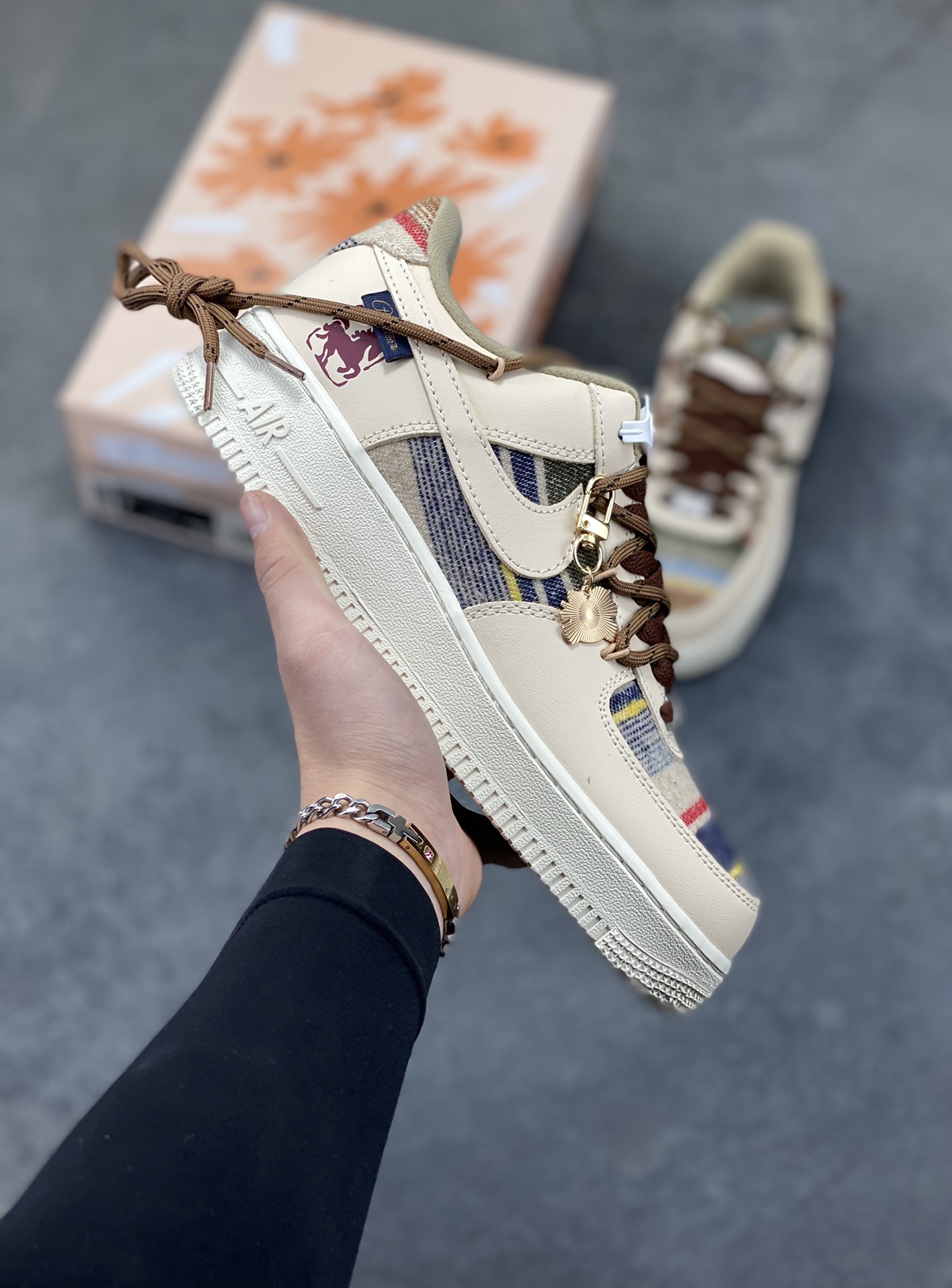 “焦糖小马”订制空军一号板鞋 该定制版球鞋选用原鞋款为Nike Air Force 1‘07空军一号，主体采用米杏色，搭配格纹布料拼接，鞋侧Swoosh也融入了格纹与纯色皮革的组合，营造出复古的美拉德色系风格。鞋带为棕色粗绳设计，配有卡通挂饰；鞋后跟处有马术风格的图案刺绣，增添了个性化元素。 货号：CW1186-230 尺码： 39 40 40.5 41 42 42.5 43 44 44.5 45-选品中心