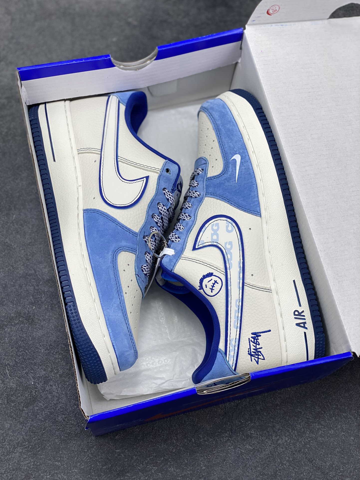 图片[9]-蓝白格调，经典焕新｜Nike Air Force 1 Low Stüssy联名款！当经典的Air Force 1 Low遇上街头潮牌Stüssy的不羁灵魂，这双SY1388-020直接把复古与潮流焊死在鞋面上！奶白皮革打底，搭配北卡蓝翻毛皮鞋头与鞋帮，撞色层次感拉满；鞋身遍布Stüssy手写签名、标志性小人logo，还有专属金属吊牌点缀，细节处全是街头态度。经典的AIR鞋底搭配Nike小勾刺绣，复古DNA刻进骨子里，上脚既适配日常穿搭，又能轻松成为造型焦点。不管是滑板街头还是城市通勤，这双蓝白配色的AF1联名款，都是你鞋柜里不可错过的潮流硬通货！-选品中心