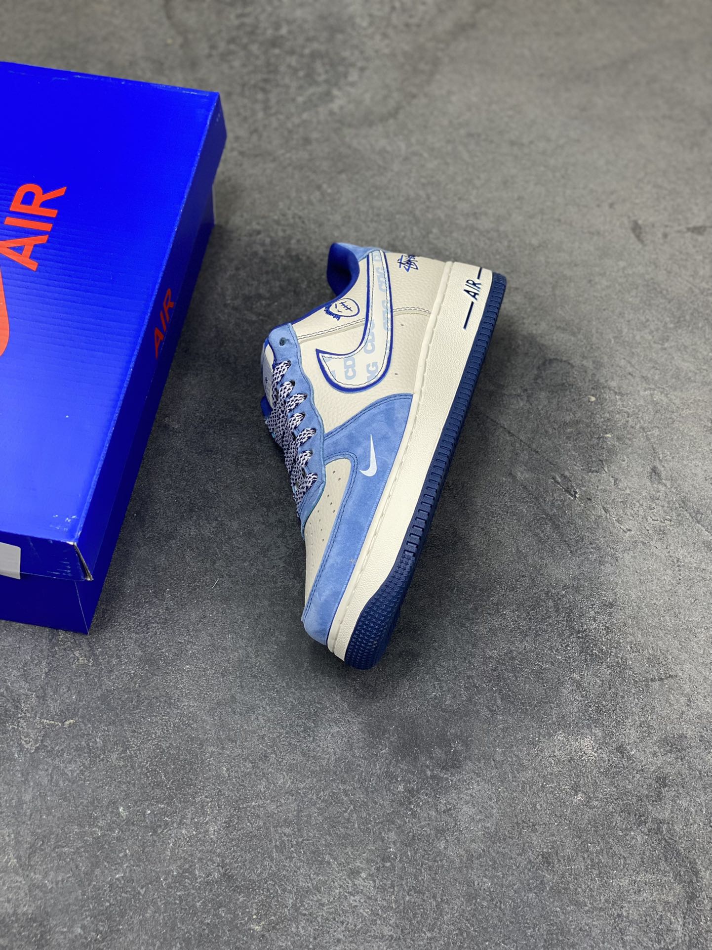 图片[7]-蓝白格调，经典焕新｜Nike Air Force 1 Low Stüssy联名款！当经典的Air Force 1 Low遇上街头潮牌Stüssy的不羁灵魂，这双SY1388-020直接把复古与潮流焊死在鞋面上！奶白皮革打底，搭配北卡蓝翻毛皮鞋头与鞋帮，撞色层次感拉满；鞋身遍布Stüssy手写签名、标志性小人logo，还有专属金属吊牌点缀，细节处全是街头态度。经典的AIR鞋底搭配Nike小勾刺绣，复古DNA刻进骨子里，上脚既适配日常穿搭，又能轻松成为造型焦点。不管是滑板街头还是城市通勤，这双蓝白配色的AF1联名款，都是你鞋柜里不可错过的潮流硬通货！-选品中心
