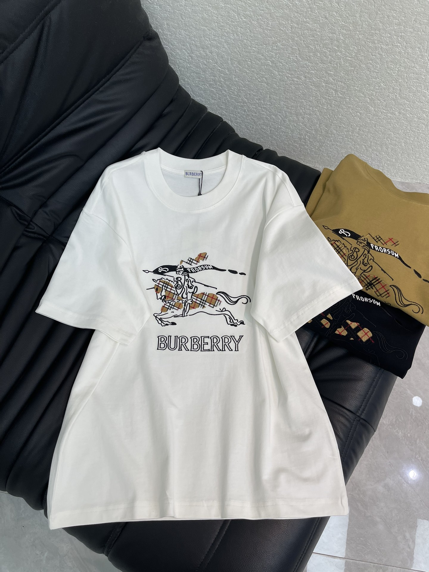 NO:708165,Burberr*26 new plaid war horse short-sleeved T-shirt. This T-shirt uses the classic plaid equestrian knight logo, and the embroidery process makes the pattern more three-dimensional and vivid. Made of high-weight pure cotton, soft and breathable, super comfortable to wear in summer. Available in three colors, versatile and fashionable, easy to control various styles. The embroidery details show the brand's craftsmanship aesthetics, and it is suitable for both casual and formal occasions! Same style for men and women!  S-XL A,,burberry,T-shirt,tees,t-shirt,19860909Burberr*26新款格纹战马短袖T恤.这款T恤采用经典格纹马术骑士徽标,刺绣工艺让图案更立体生动.高克重纯棉材质,柔软透气,夏天穿超舒服.三色可选,百搭又时髦,轻松驾驭各种风格.刺绣细节展现品牌工艺美学,无论休闲还是正式场合都很适合哦!男女同款！S-XL A,,burberry,T-shirt,tees，t-shirt,,Women's clothing