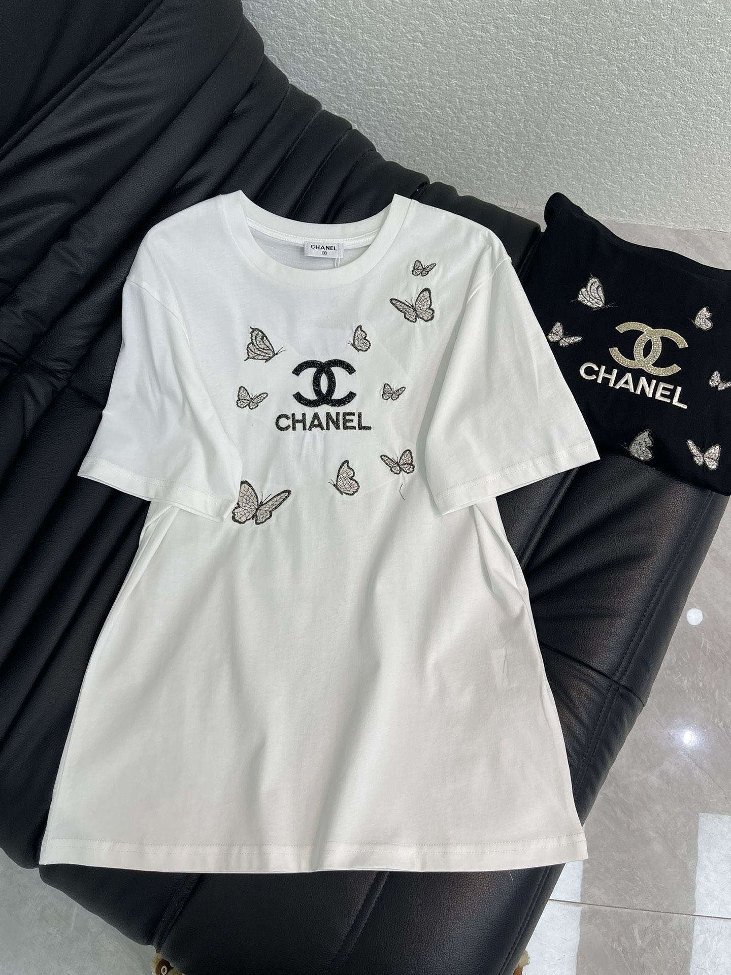 NO:697667,Chane*26 new spring and summer embroidered letter logo short-sleeved T-shirt. Customized YB mercerized cotton material, breathable and comfortable, full of texture, regular short-sleeved T-shirt cut, butterfly hot diamond black T welds romance and high-end to the body!  The white background is lined with shining butterfly hot diamonds, and the double C logo is smart and eye-catching. The simple letter logo low-key highlights the brand style. The soft cotton fabric is skin-friendly and breathable, and the loose version hides flesh and is casual. It is a sweet and cool tool when worn alone, and can be layered to easily create a sense of layering. It is a versatile treasure that cannot be missed in the wardrobe. SML A,,chanel,T-shirt,tees,t-shirt,19860909Chane*26春夏新款刺绣字母徽标短袖T恤.定制YB丝光全棉材质,透气舒适,质感十足,常规短袖T恤裁剪,蝴蝶烫钻黑T把浪漫与高级焊在了衣身！白底衬着闪耀的蝴蝶烫钻,环绕双C Logo灵动又吸睛,简约的字母标识低调彰显品牌格调.柔软的棉质面料亲肤透气,宽松的版型藏肉又随性,单穿是甜酷利器,叠穿也能轻松打造层次感,是衣橱里不可错过的百搭宝藏款.SML A,,chanel,T-shirt,tees，t-shirt,,Women's clothing