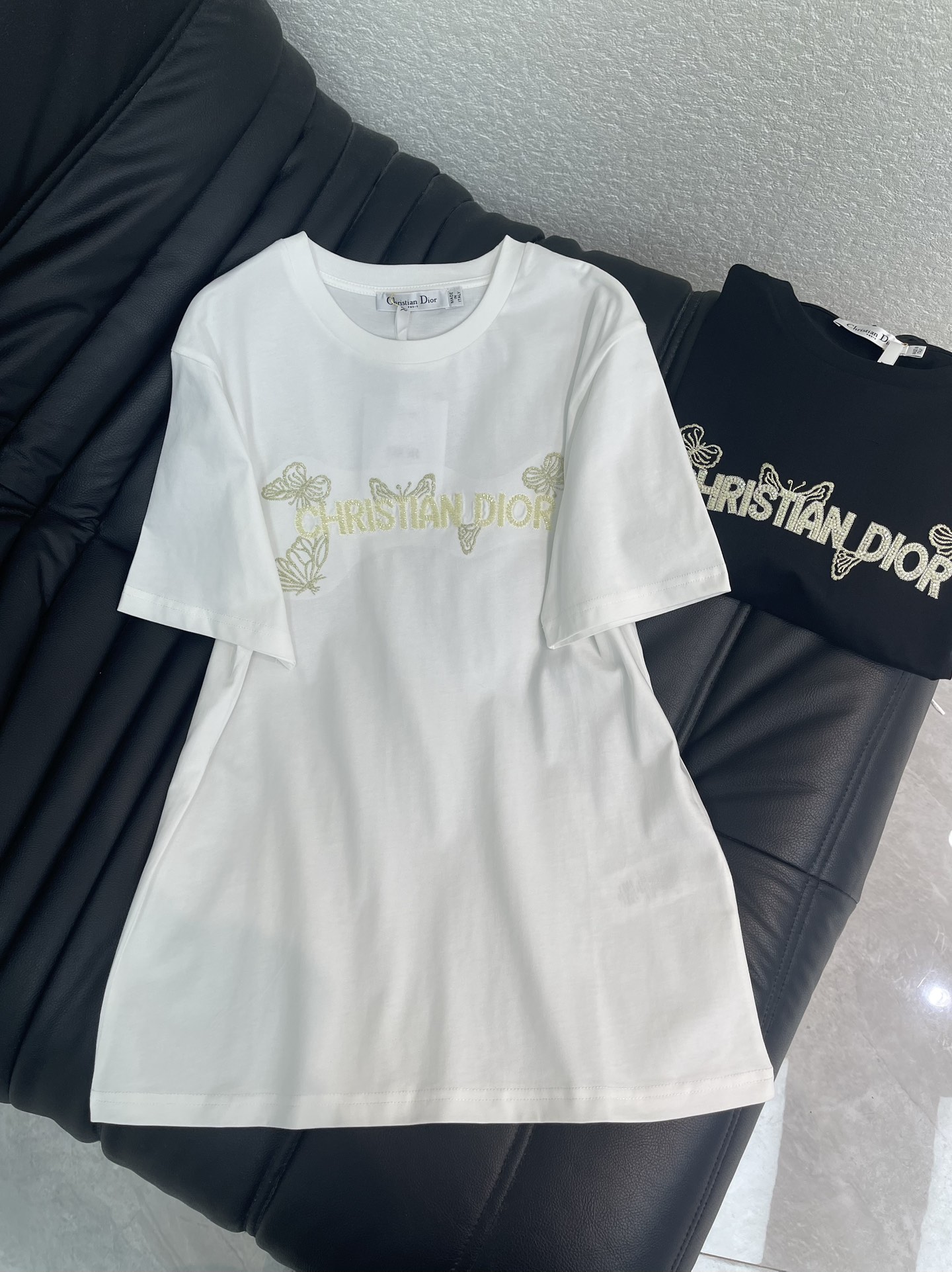 NO:708504,Dio*26 new spring and summer embroidered beaded butterfly logo short-sleeved T-shirt. Customized YB mercerized cotton material, breathable and comfortable, full of texture, regular T-shirt cutting, heavy butterfly embroidery beaded, perfectly blending romance and luxury texture, pure white style is fresh and elegant, pure black is cool and elegant, gold  The colorful embroidered letters are paired with smart butterfly patterns, and the details are full of exquisiteness and ingenuity. The soft cotton fabric is skin-friendly and breathable, and the regular version hides flesh and is casual. It is an eye-catcher when worn alone, and can be easily layered when layered. It is a versatile treasure in the wardrobe that combines appearance and practicality. SML  A,,dior,T-shirt,tees,t-shirt,19860909Dio*26春夏新款刺绣订珠蝴蝶徽标短袖T恤.定制YB丝光全棉材质,透气舒适,质感十足,常规T恤裁剪,重工蝴蝶刺绣订珠,将浪漫与高奢质感完美糅合,纯白款清新雅致,纯黑酷飒大气,金色刺绣字母搭配灵动蝴蝶图案,细节处尽显精致巧思.柔软的棉质面料亲肤透气,常规的版型藏肉又随性,单穿是的吸睛利器,叠穿也能轻松打造层次感,是衣橱里兼具颜值与实用性的百搭宝藏款.SML A,,dior,T-shirt,tees，t-shirt,,Women's clothing